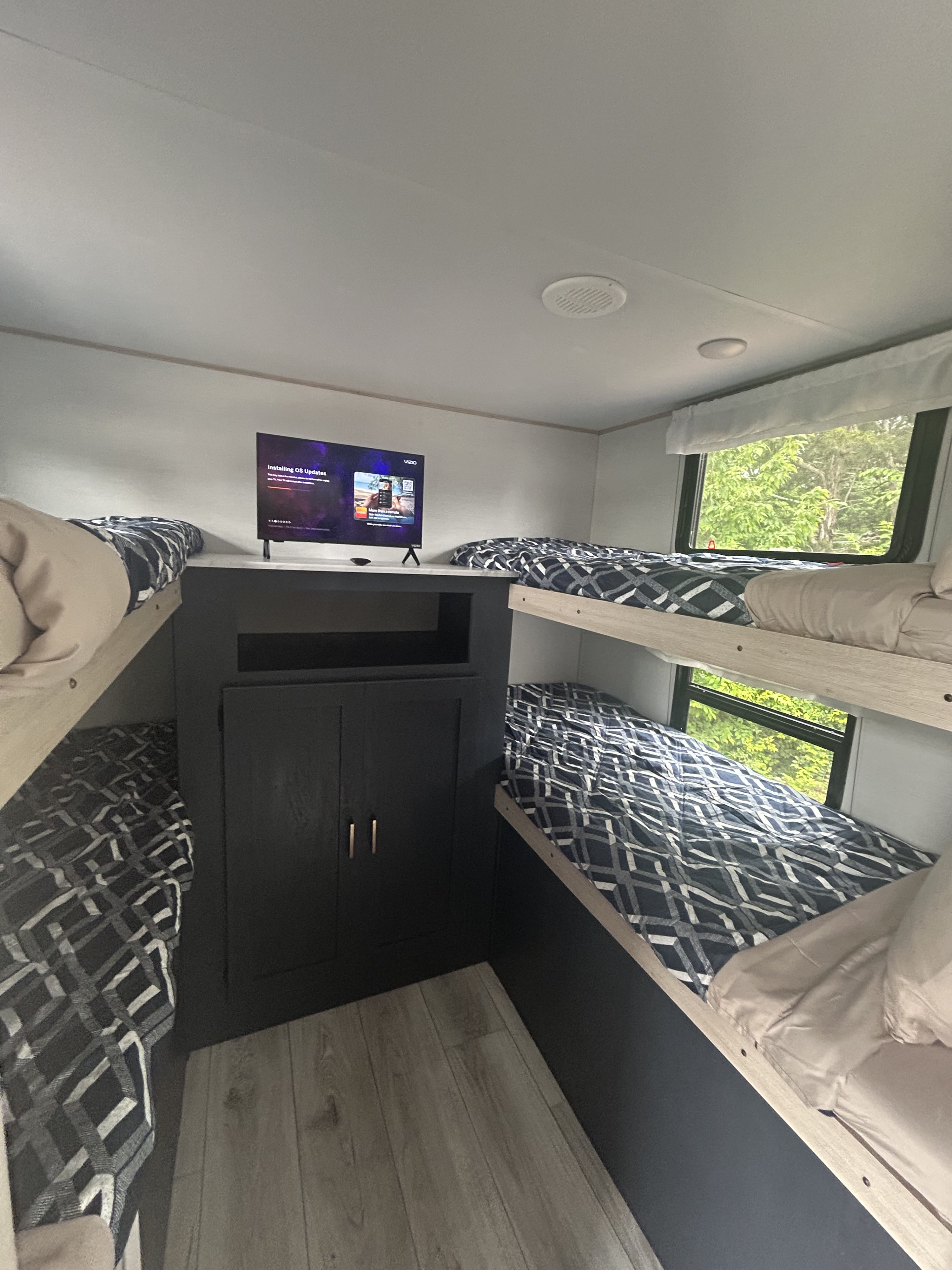 Modern RV rental interior featuring multiple bunk beds, central entertainment TV, and wood floors.. Forest River 2339176 2024