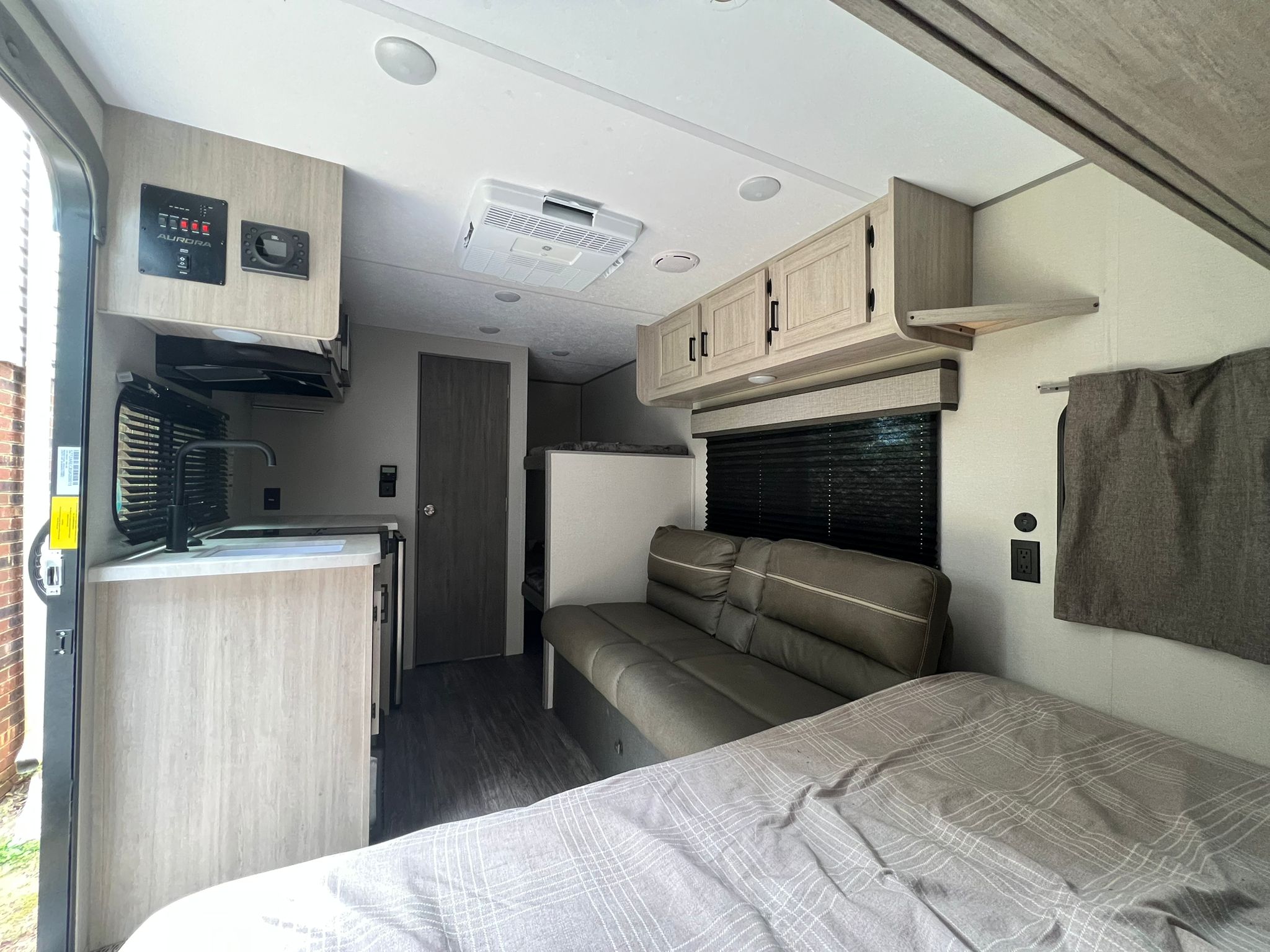 Spacious RV rental interior featuring a cozy bed, comfortable couch, and functional kitchen, perfect for travel adventures.. Forest River Aurora Aurora 2025