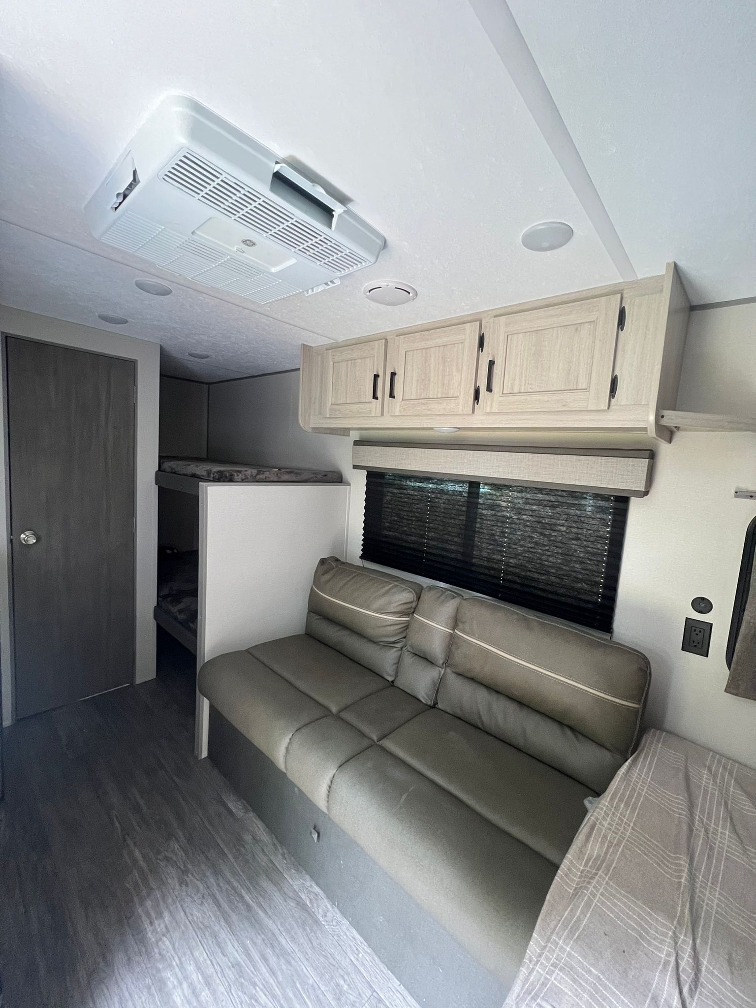 Cozy rv rental interior with sofa, bunk beds, overhead cabinets, and ceiling AC unit for your trip.. Forest River Aurora Aurora 2025