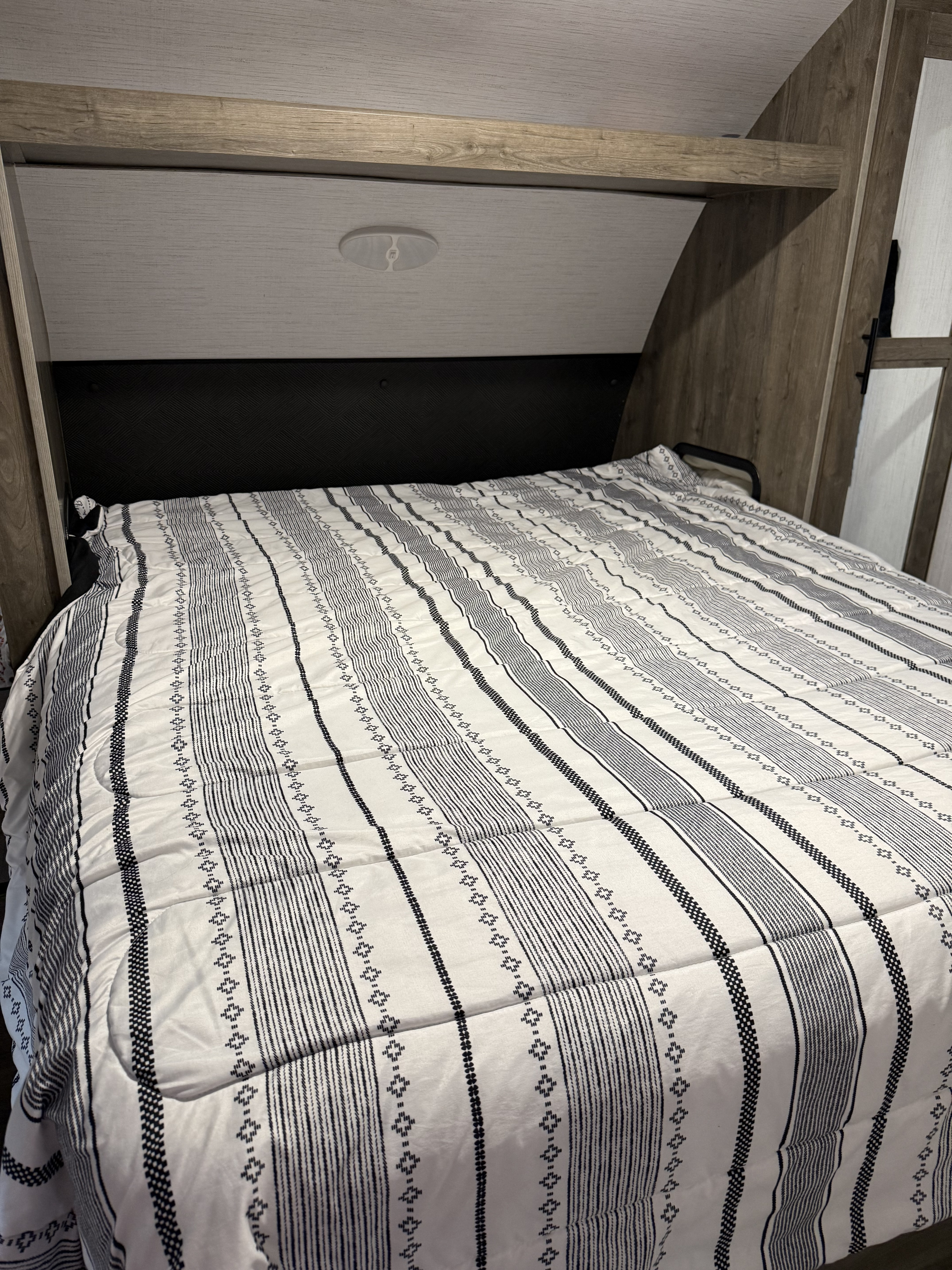 Modern RV rental bedroom featuring a comfy bed with a stylish black and white striped comforter and wood accents.. 5SFPB372XME475890 Pioneer 2021