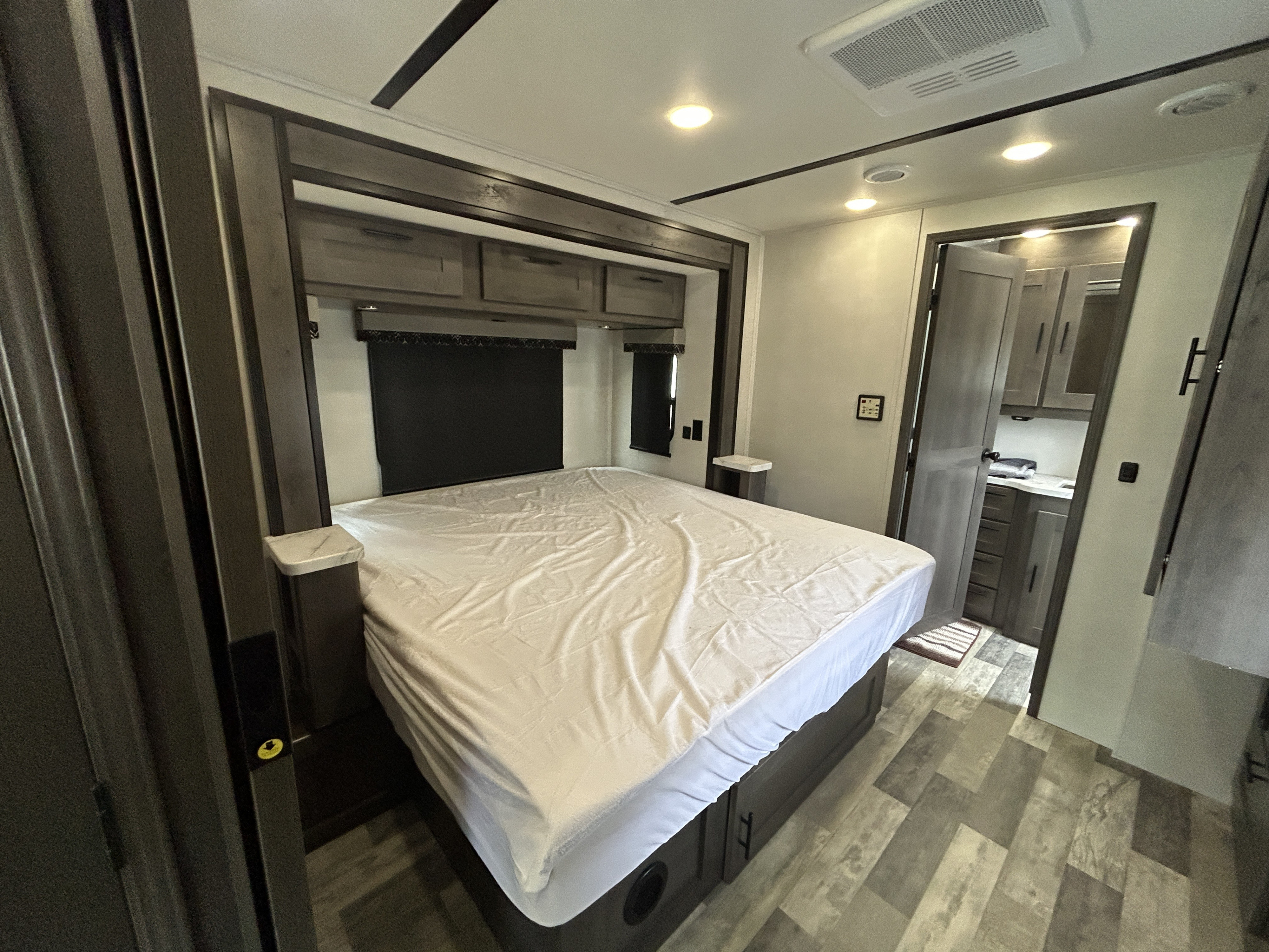 Spacious RV rental bedroom featuring a large bed, overhead storage, and an attached private bath, ideal for comfortable travel.. Forest River Fr3 2021