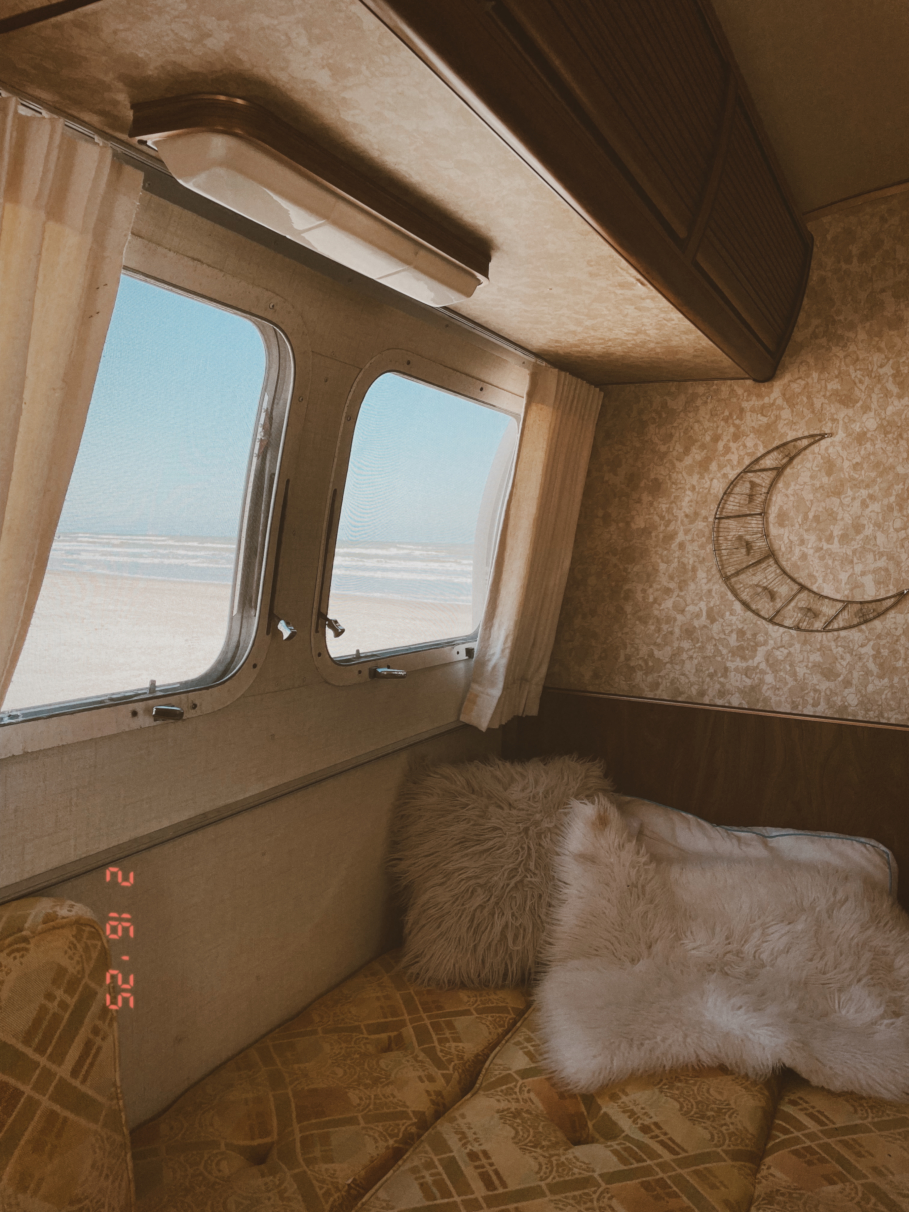 Relax in this cozy rv rental! Panoramic windows reveal a beach view, complemented by plush cushions & a moon decor.. Airstream Argosy 1977