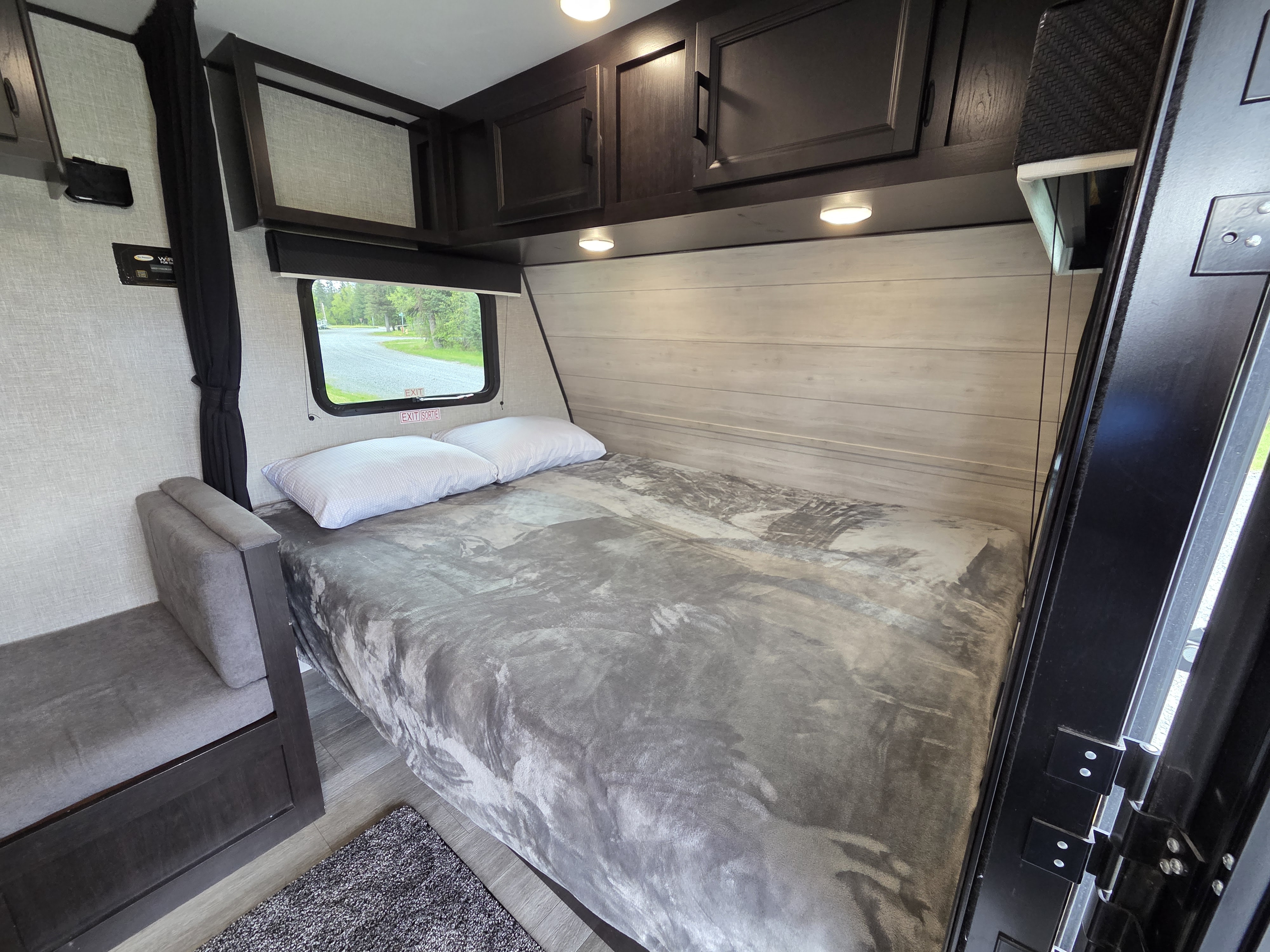 Experience comfort in this RV rental's bedroom, featuring a bed, bench, window, and overhead storage.. Jayco Jay Flight SLX Baja Edition 2022