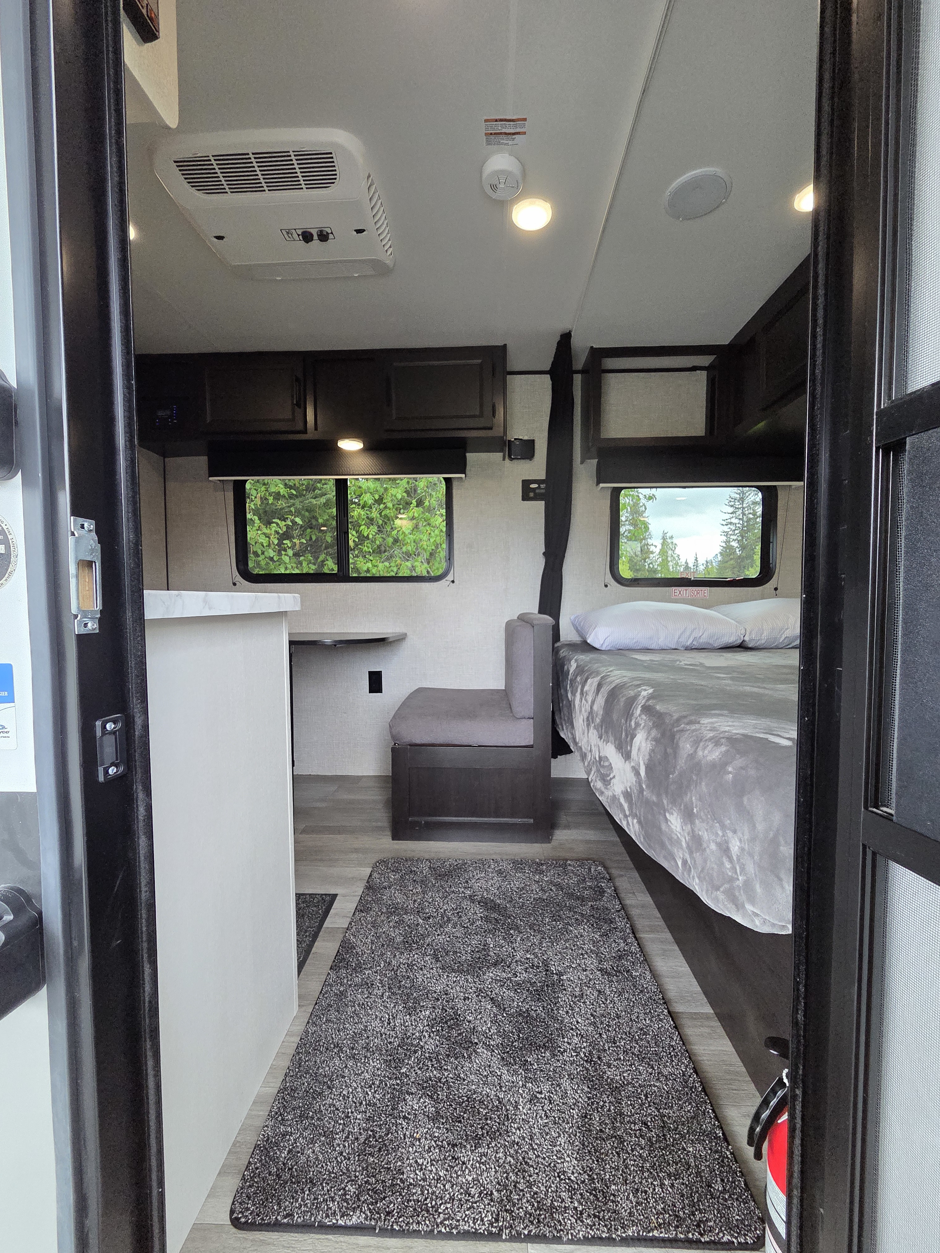 Step inside a modern rv rental. This cozy camper interior features a bed, seating, small kitchen counter, and ceiling AC unit.. Jayco Jay Flight SLX Baja Edition 2022