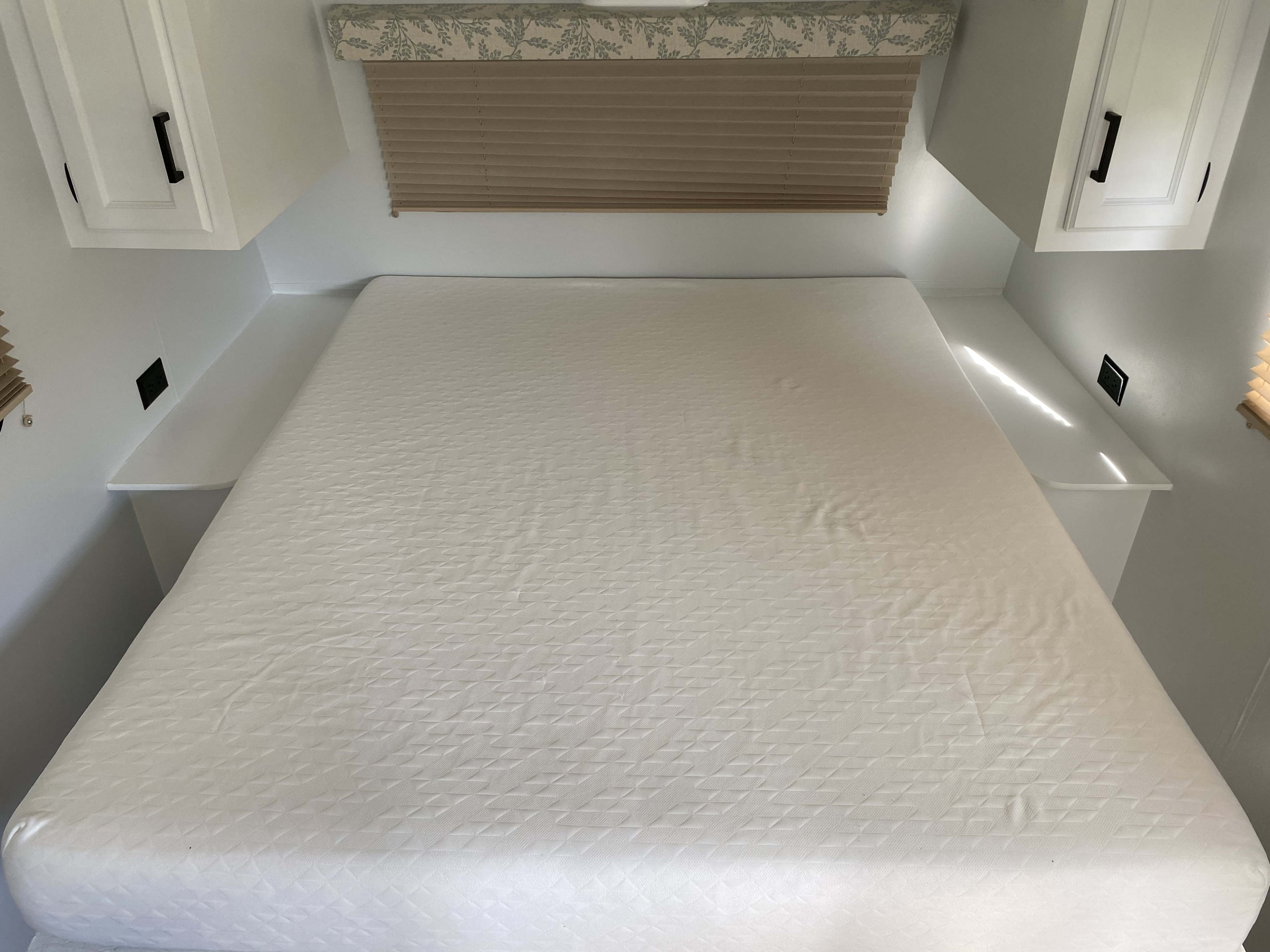 Clean, modern RV rental bedroom with white quilted bed, built-in shelves, and overhead cabinets.. Jayco Jay Flight SLX Baja Edition 2015