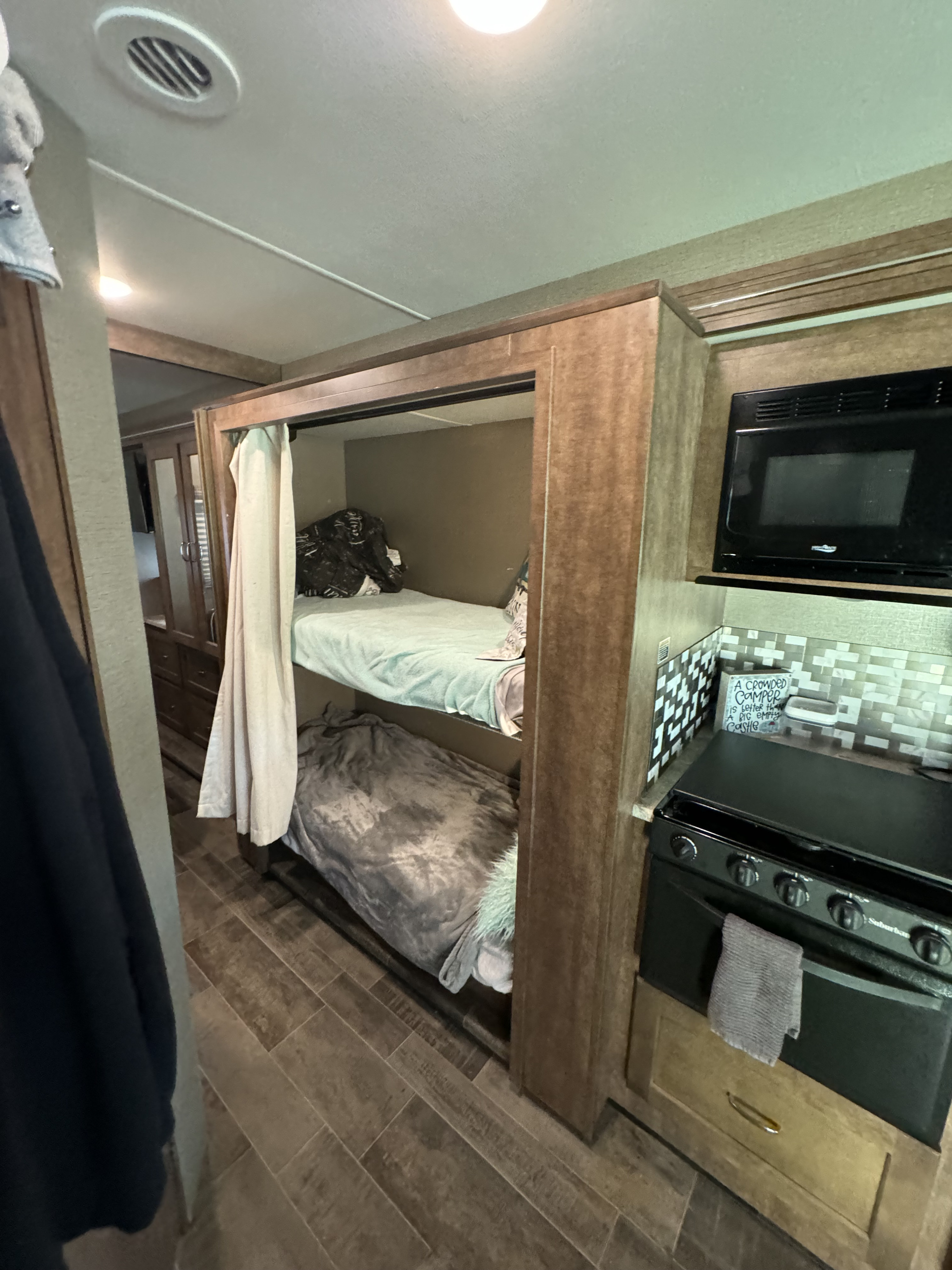 Cozy RV rental interior featuring bunk beds, a compact kitchen with microwave and stove, maximizing space.. Winnebago Intent 2018