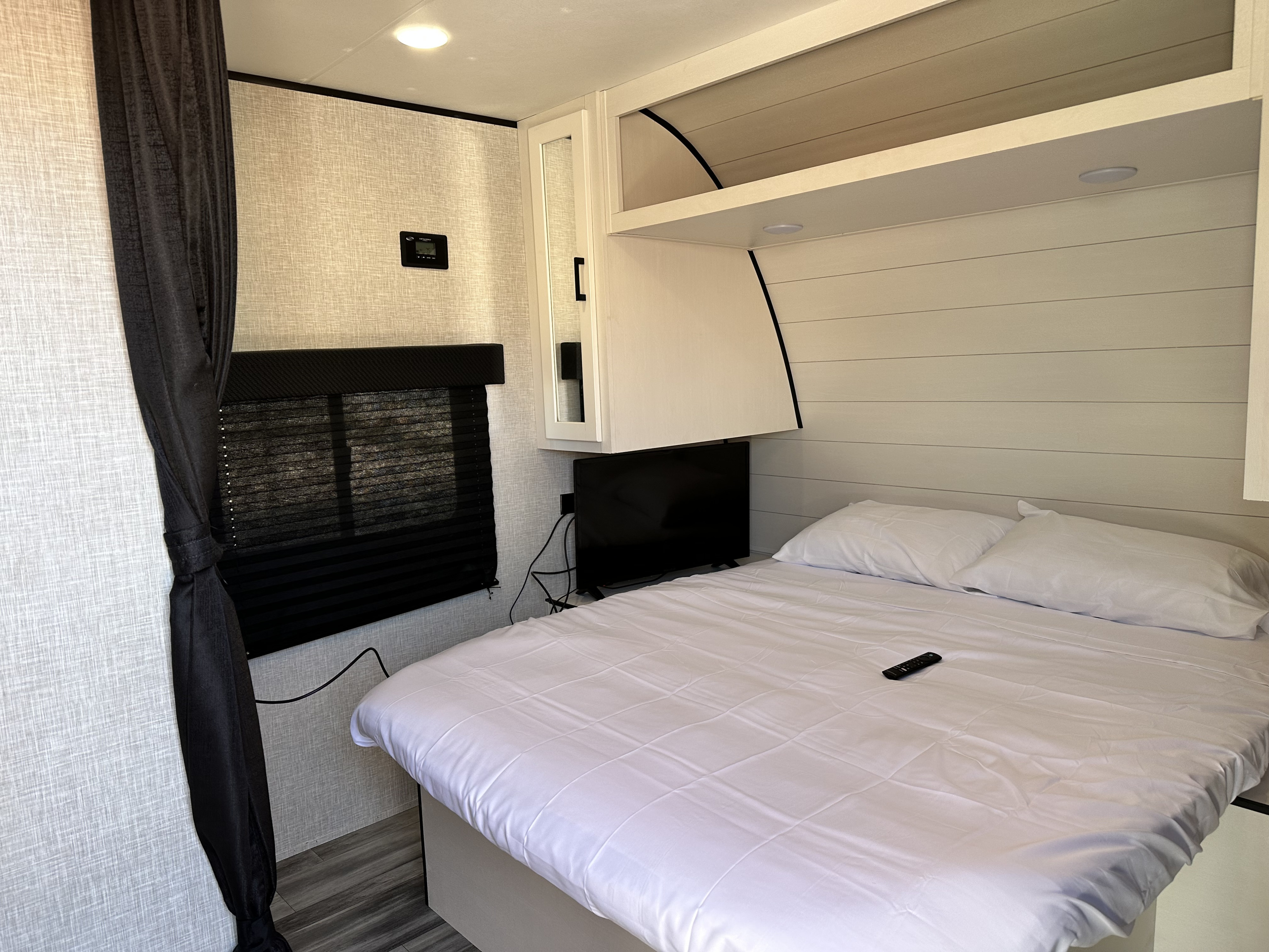 RV rental: Bright bedroom featuring a comfy bed with white linens, a TV, overhead storage, and blackout blinds for comfort.. Jayco Jay Flight SLX 2024