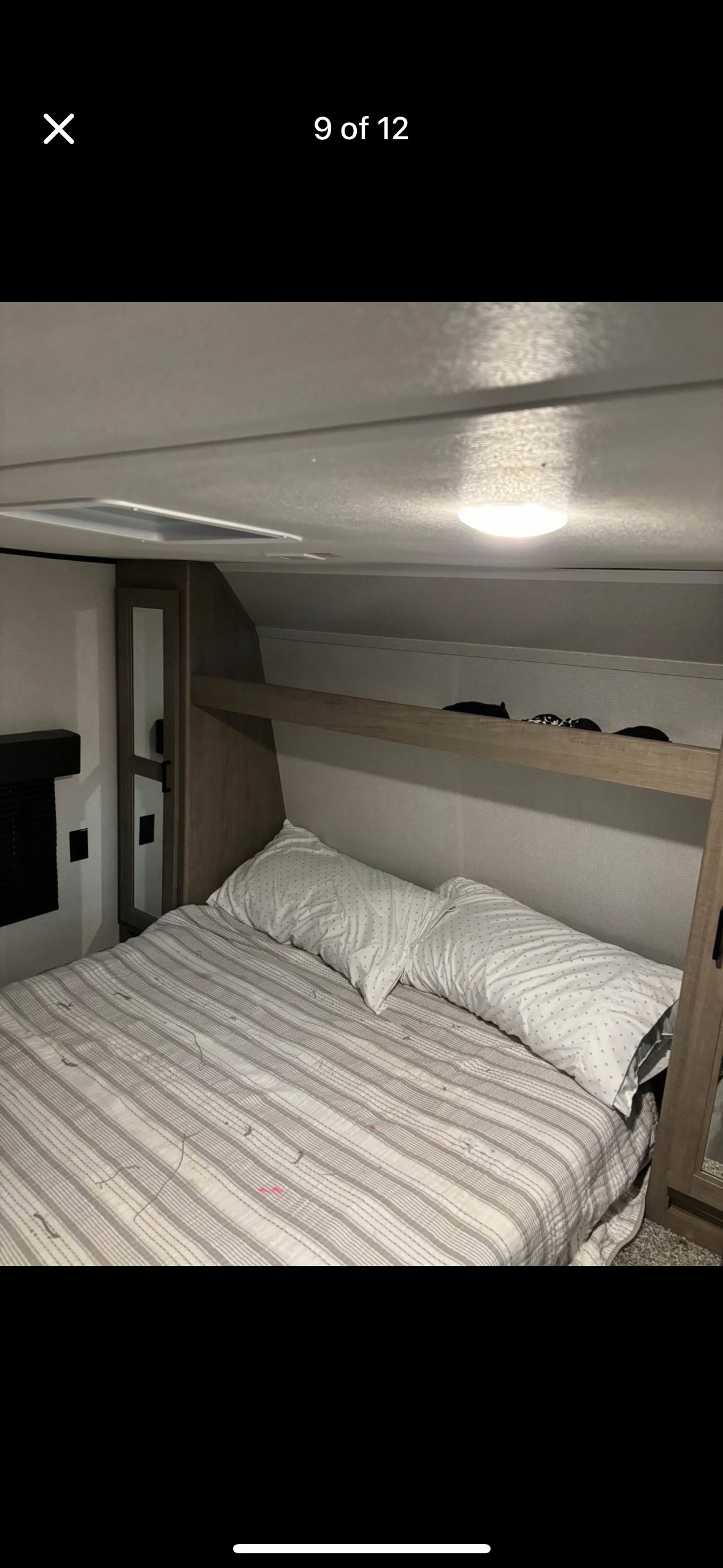 Cozy RV rental bedroom featuring striped bedding, pillows, overhead storage, and a mirrored wardrobe for comfortable travel.. Keystone RV Hideout 2021
