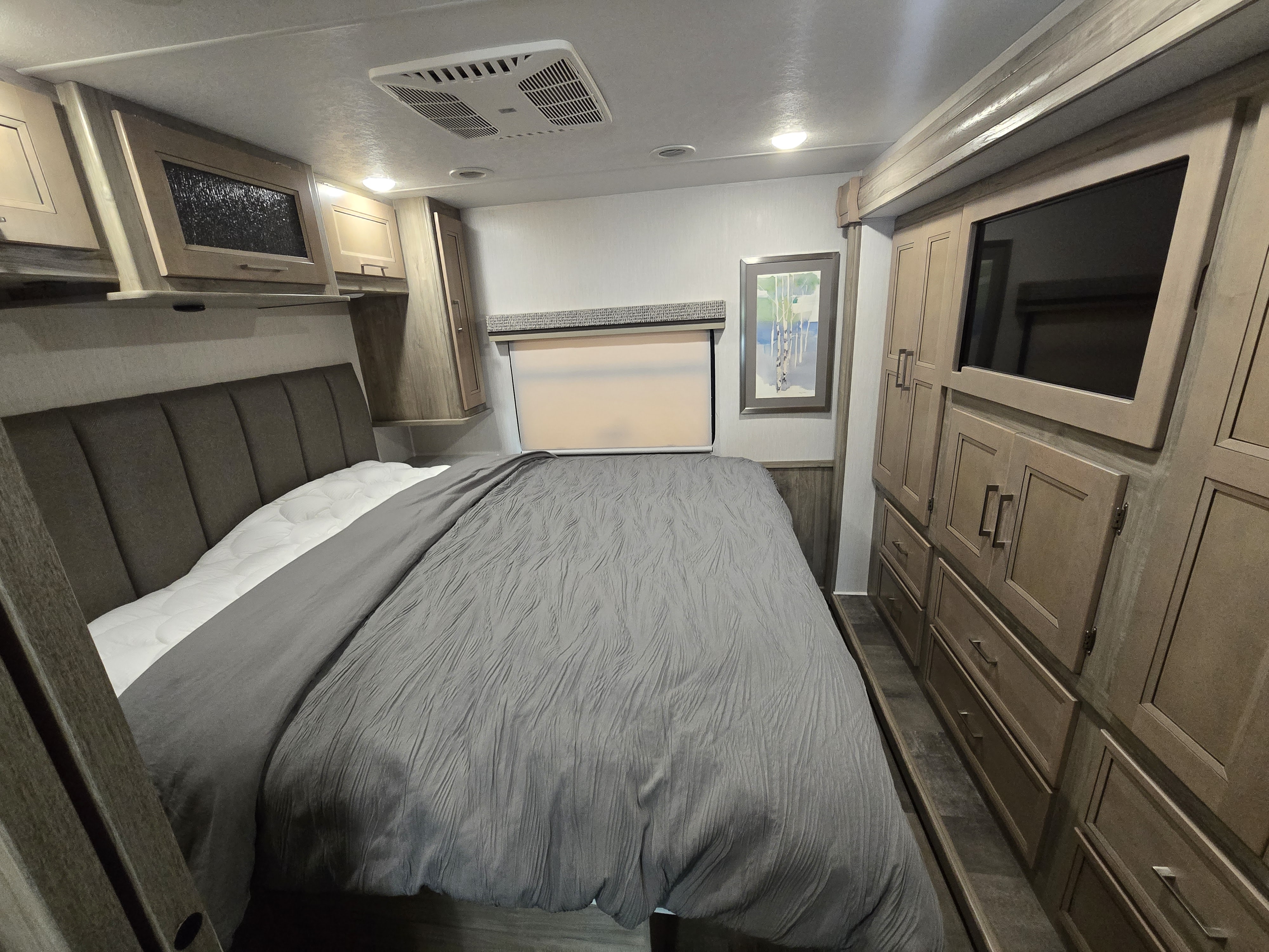 Inside a comfortable RV rental: master bedroom featuring bed, overhead storage, and entertainment center.. Coachmen Mirada 2020