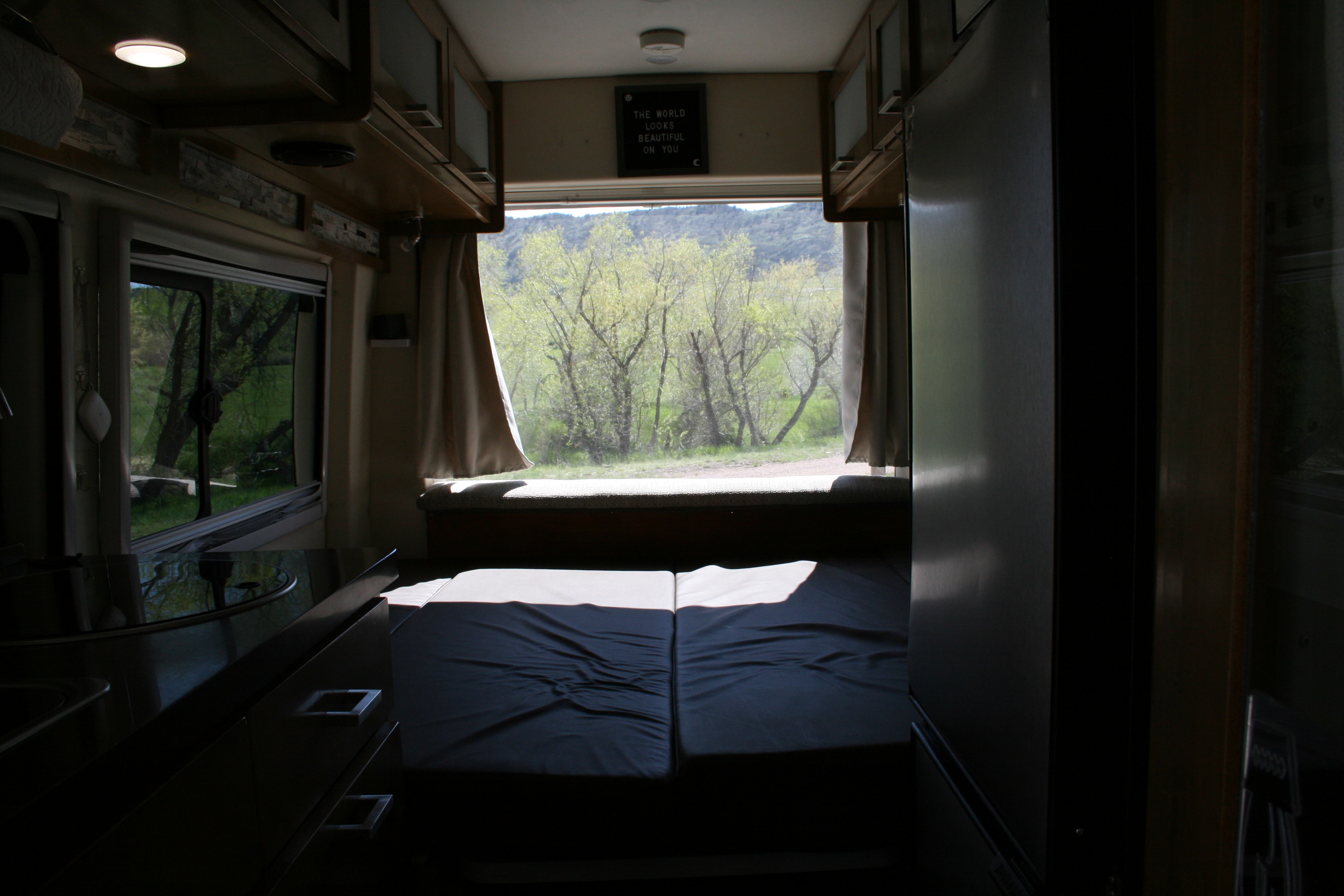 Step inside this RV rental: a comfy bed, kitchen area, and a large rear window offering stunning views of green trees and mountains.. Forest River Coachmen Crossfit 2018