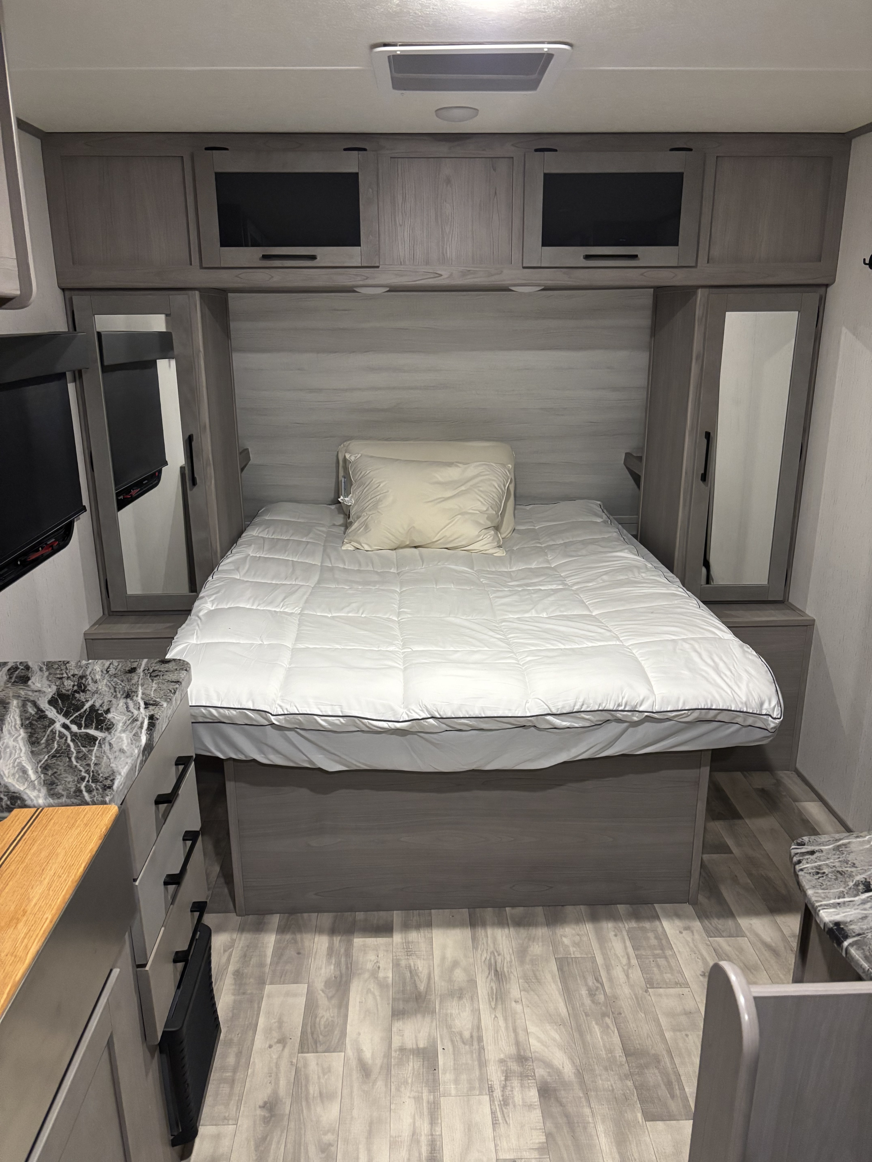 Bright RV rental bedroom: large bed, smart storage solutions, and modern grey wood interior.. Dutchmen Kodiak Ultra Lite 2023