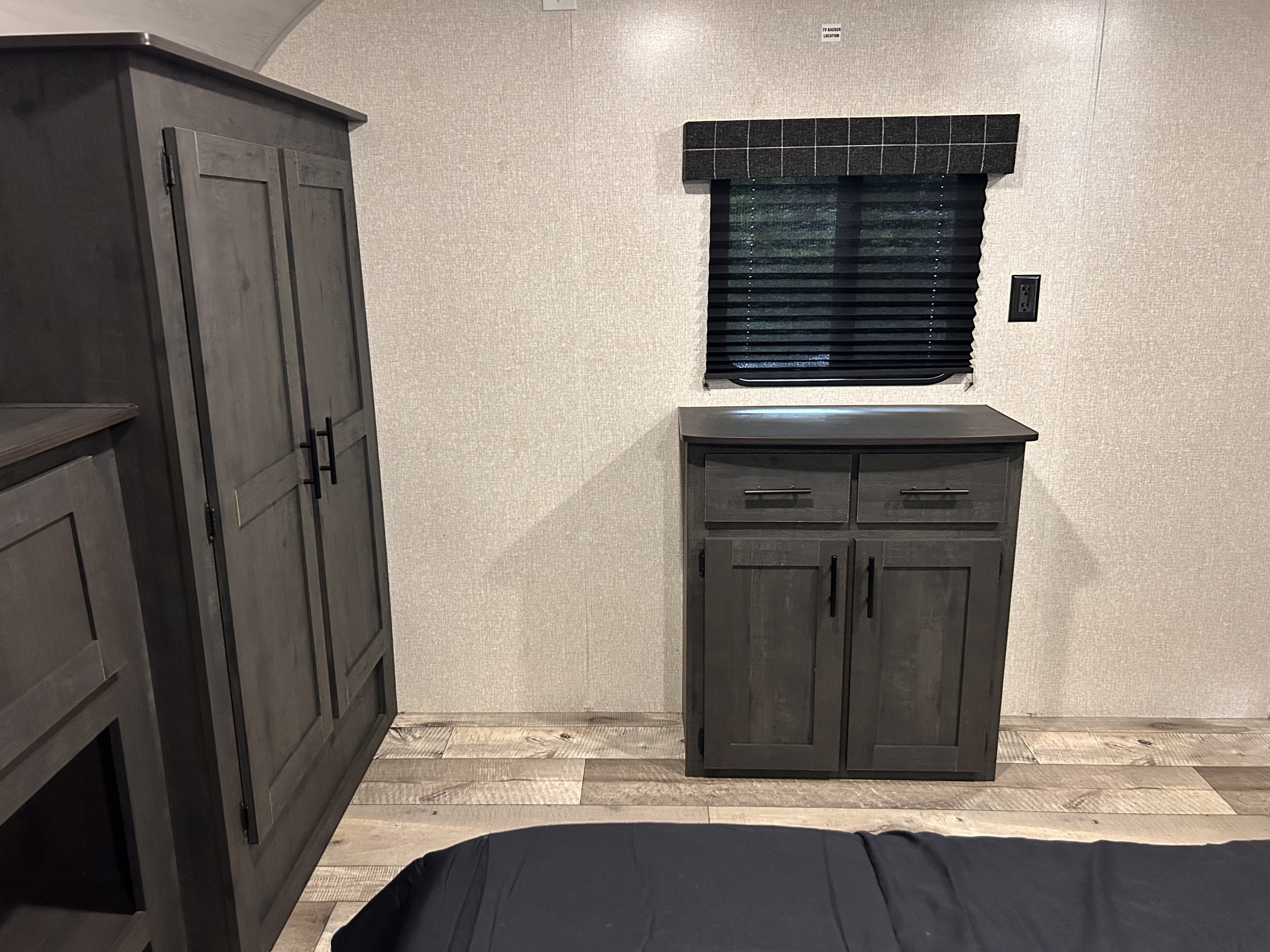 RV rental bedroom with dark wood wardrobe, dresser, window with blinds, and light textured walls.. Sportsmen SE 2022