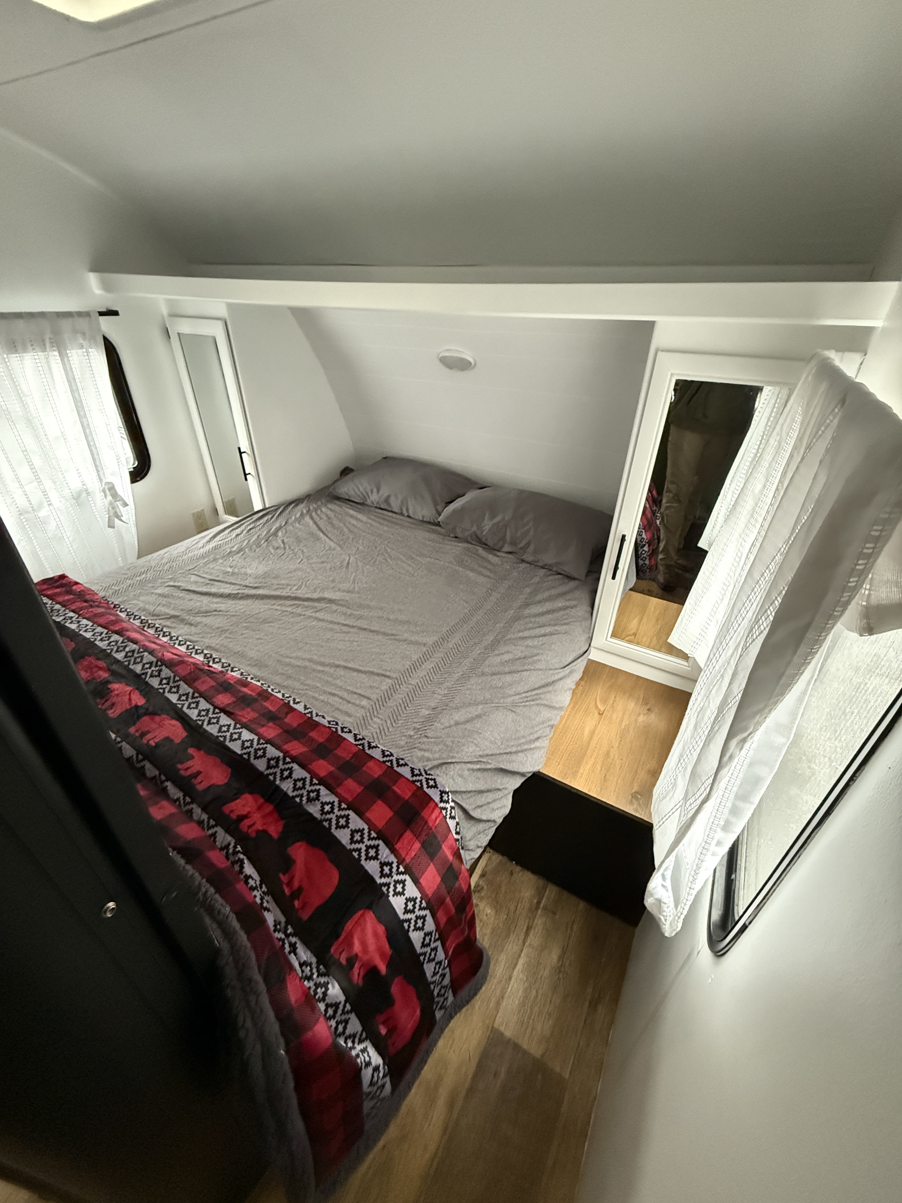 Inside a compact rv rental, a cozy bedroom features a bed with grey bedding, a unique bear-patterned blanket, and mirrors.. Forest River Cruise lite 2017