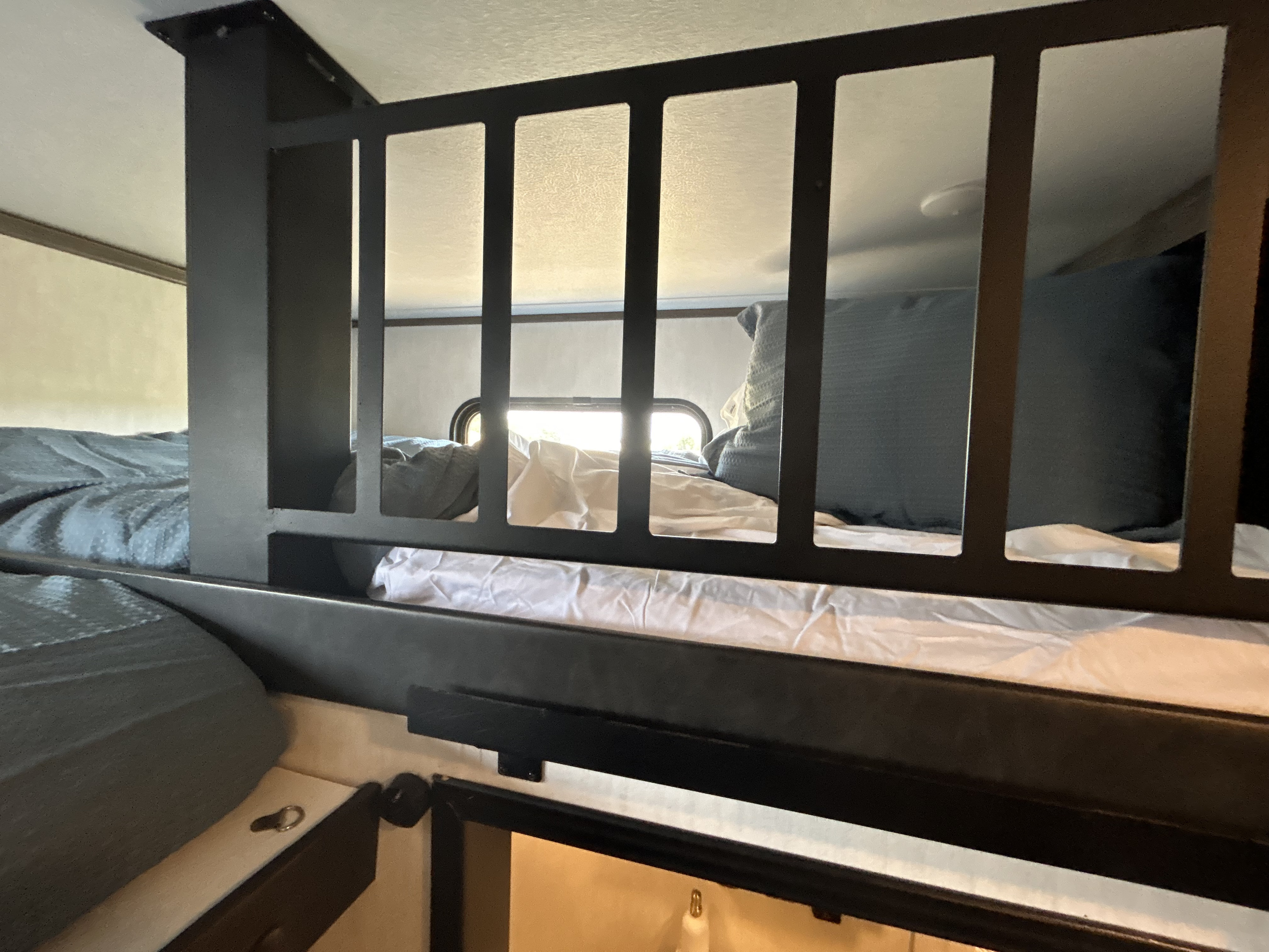 RV rental interior, showing cozy bunk beds with dark metal safety rails, perfect for family travel.. Forest River Sabre 2021