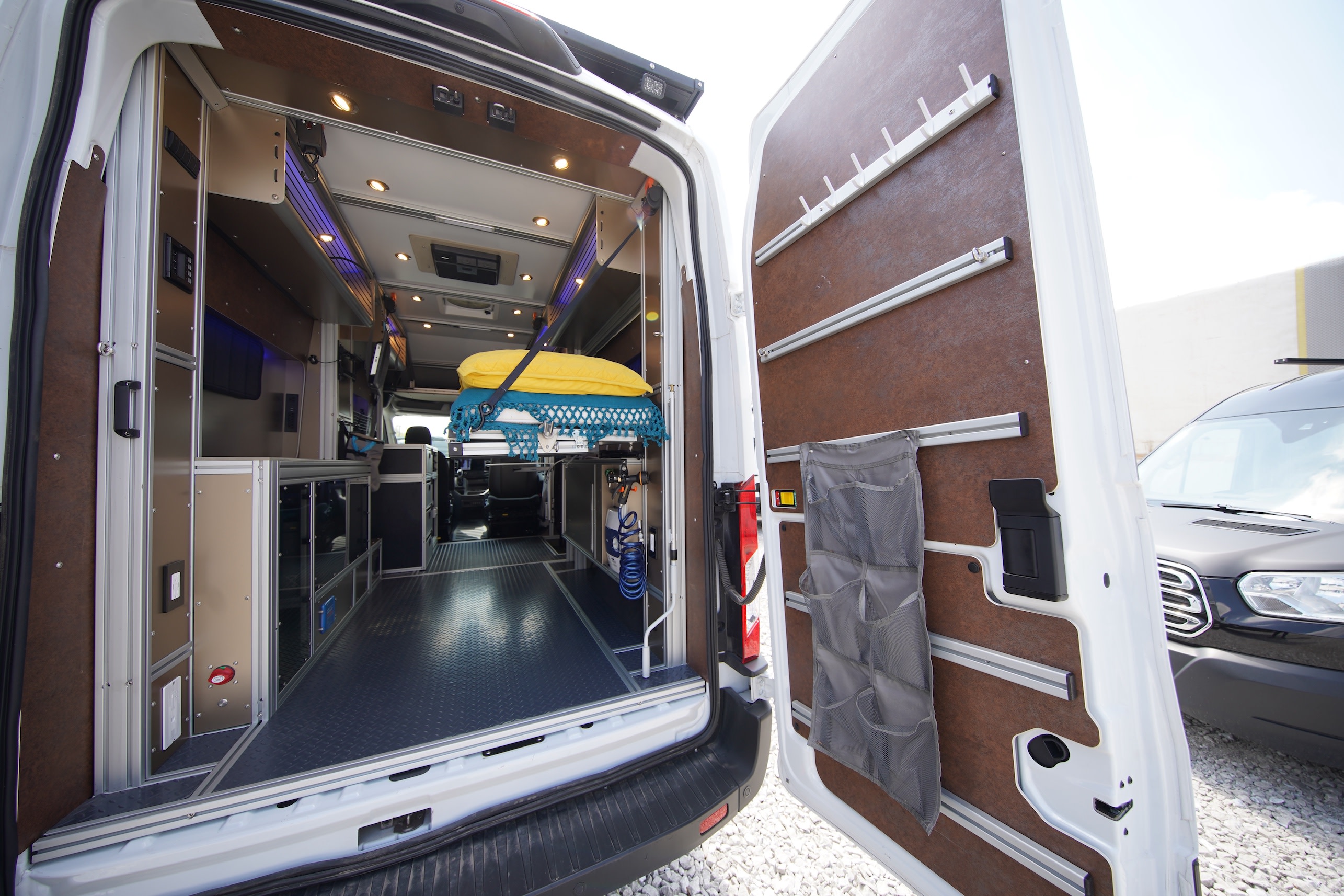Rear interior of a versatile RV rental, showcasing modular aluminum and wood panels, smart storage, and a suspended bed.. Vandoit MOOV 2023