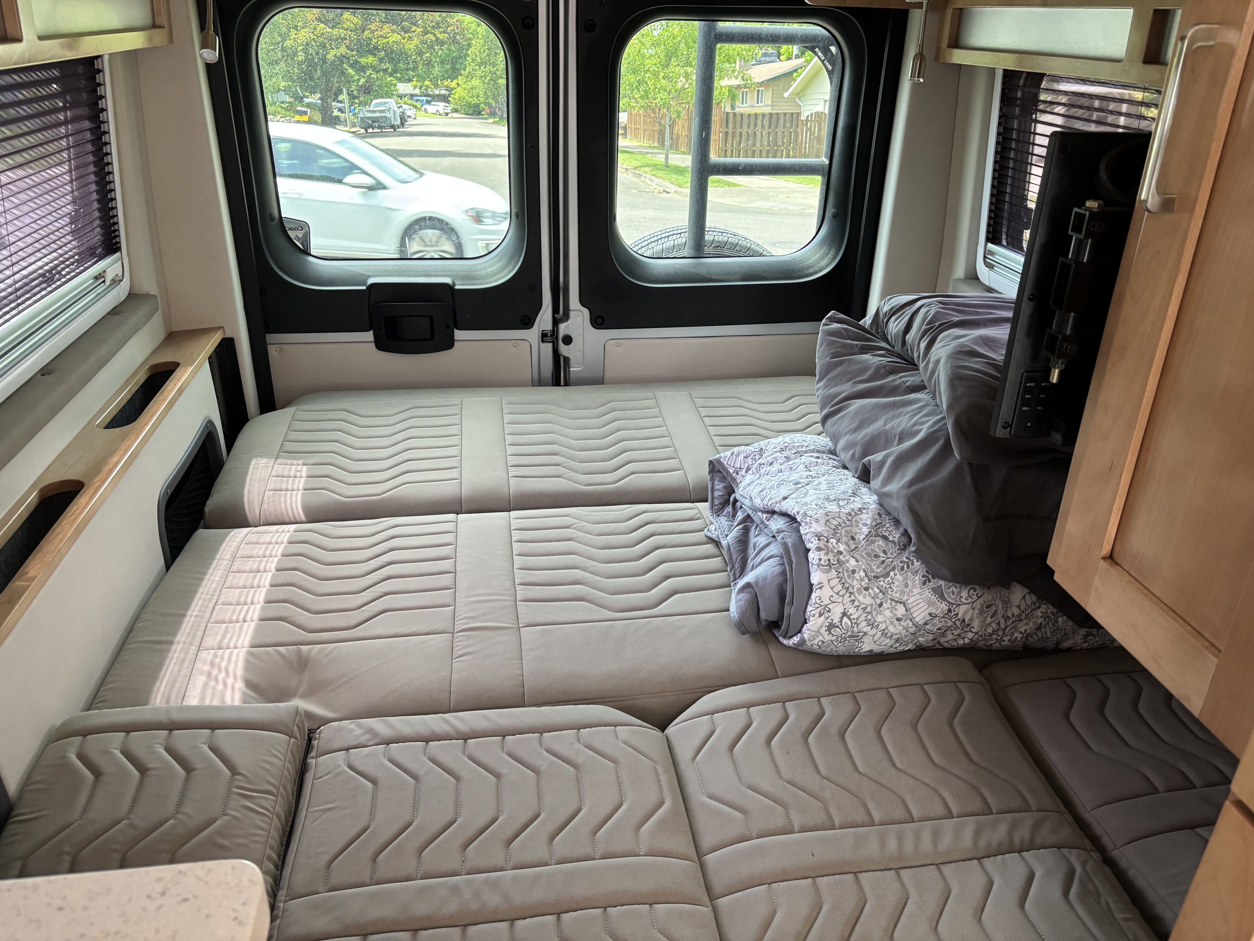 Cozy RV rental interior with a spacious bed/seating area, comfortable cushions, and views of the street outside.. Coachman Nova 2024