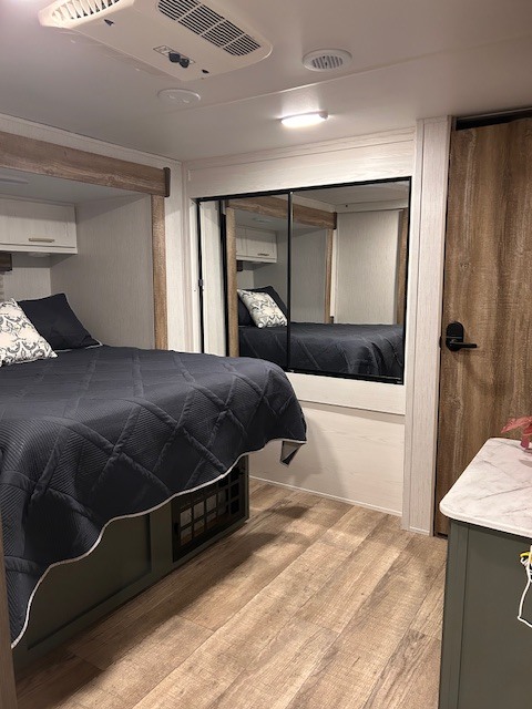 Inside a modern RV rental bedroom featuring a bed, mirrored closet, and AC unit for comfort.. Heartland RVs Eddie Bauer 34BSBH 2024