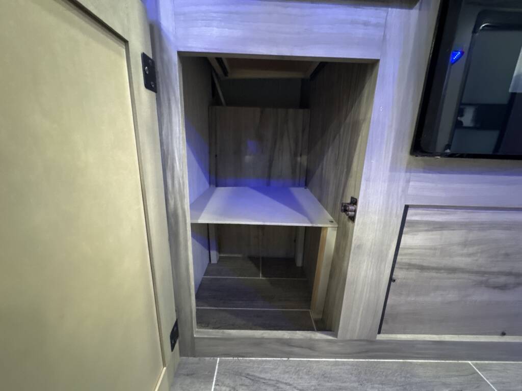 RV rental: Open storage cubby with a shelf in a modern grey wood-grain cabinet, suitable for electronics.. Forest River Cherokee Alpha Wolf 2020