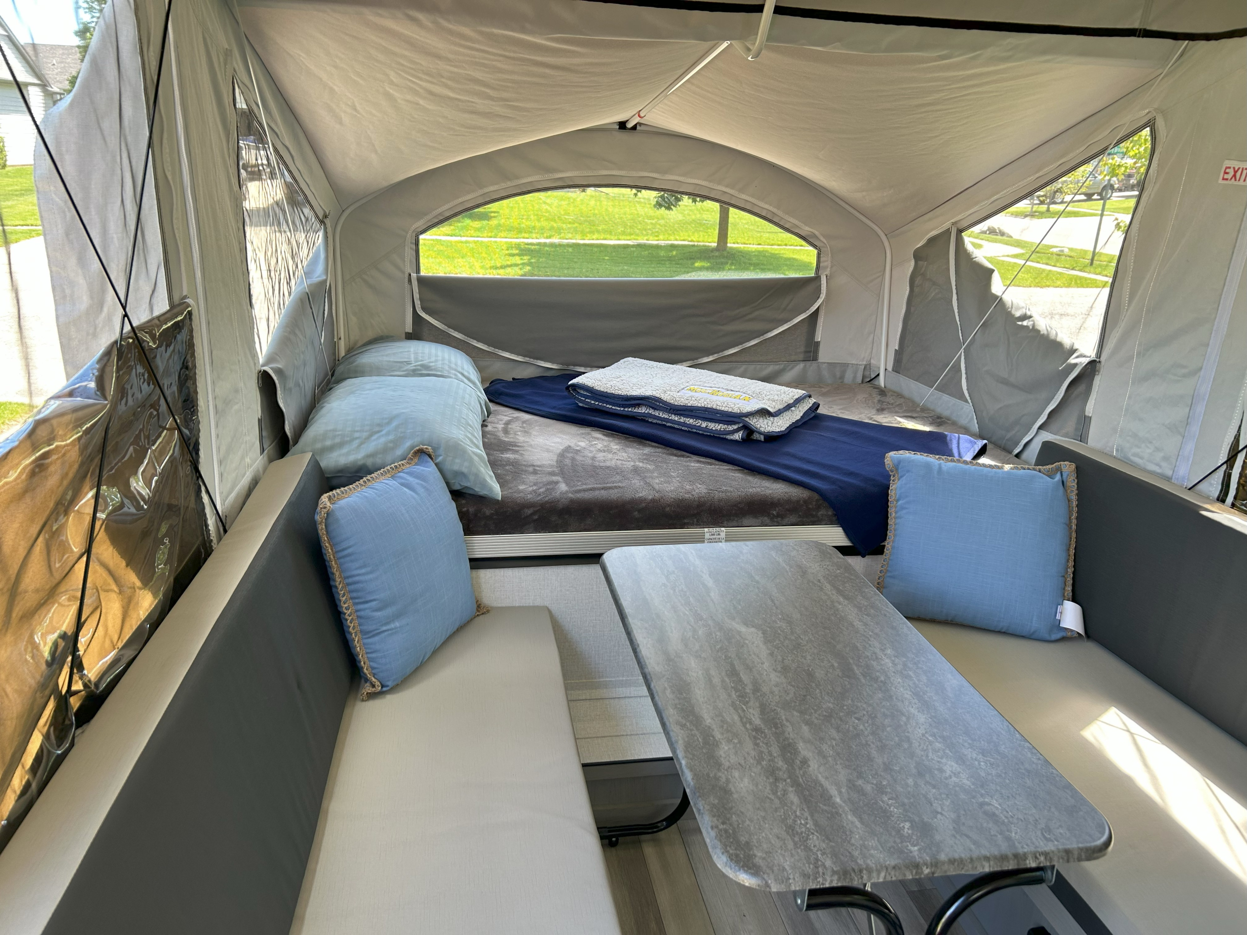 Spacious interior of an RV rental pop-up camper, featuring a cozy bed and dinette area with light-filled windows.. Coachmen Clipper 806XLSLE Clipper 2024