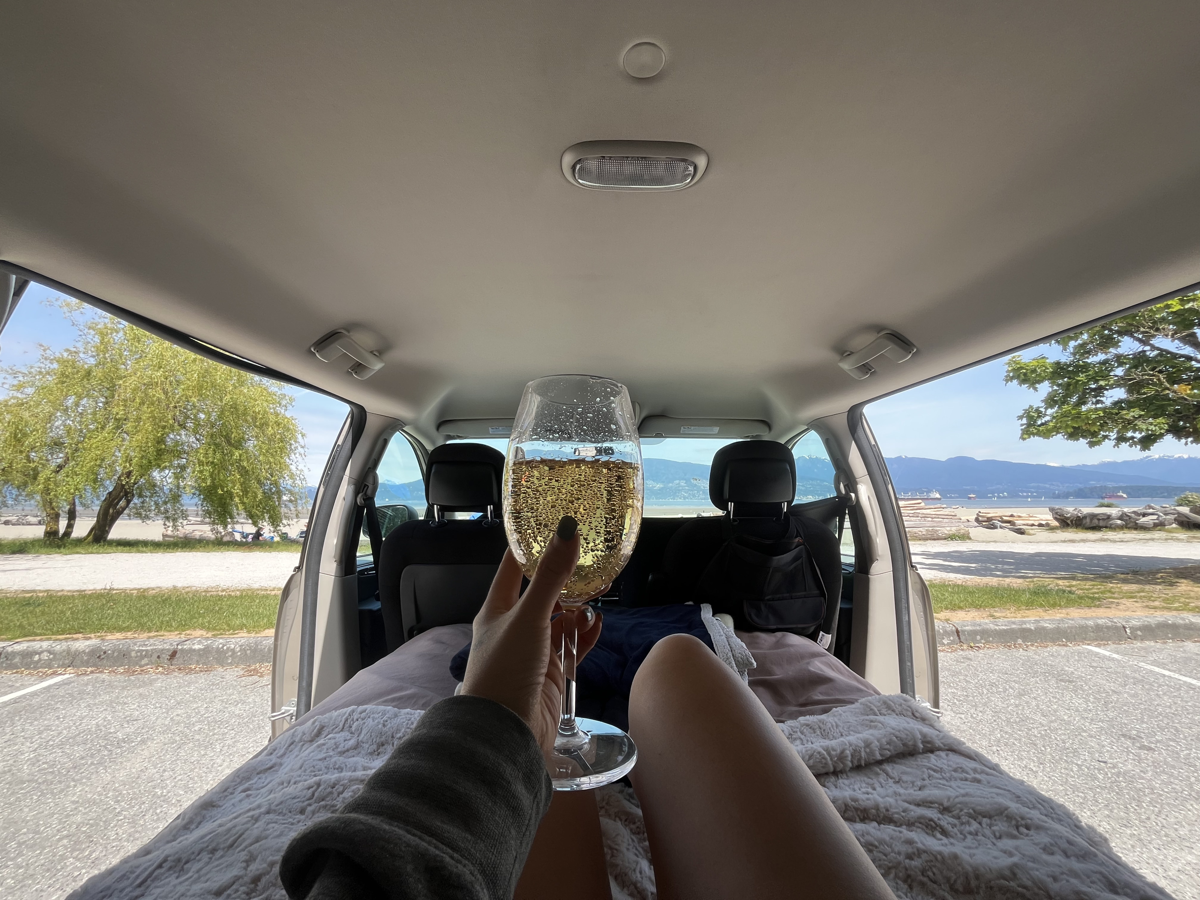 Enjoying a relaxing moment in a cozy rv rental with a sparkling drink, overlooking a beautiful bay and mountains.. Dodge Grand Caravan 2014