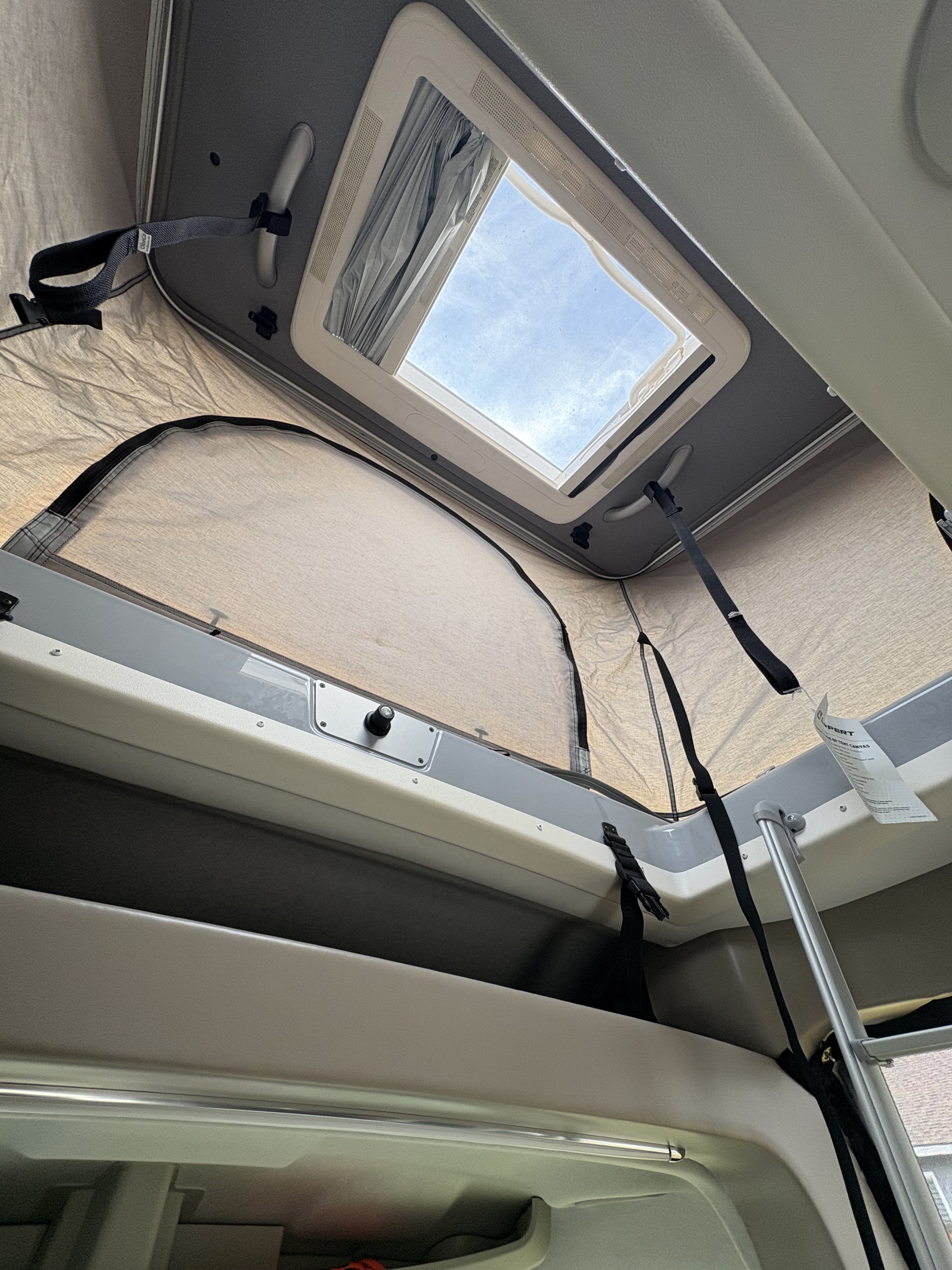 RV rental: Inside view of a camper's pop-top tent, showcasing the open skylight and light fabric walls.. Thor Motor Coach Spartan 2024