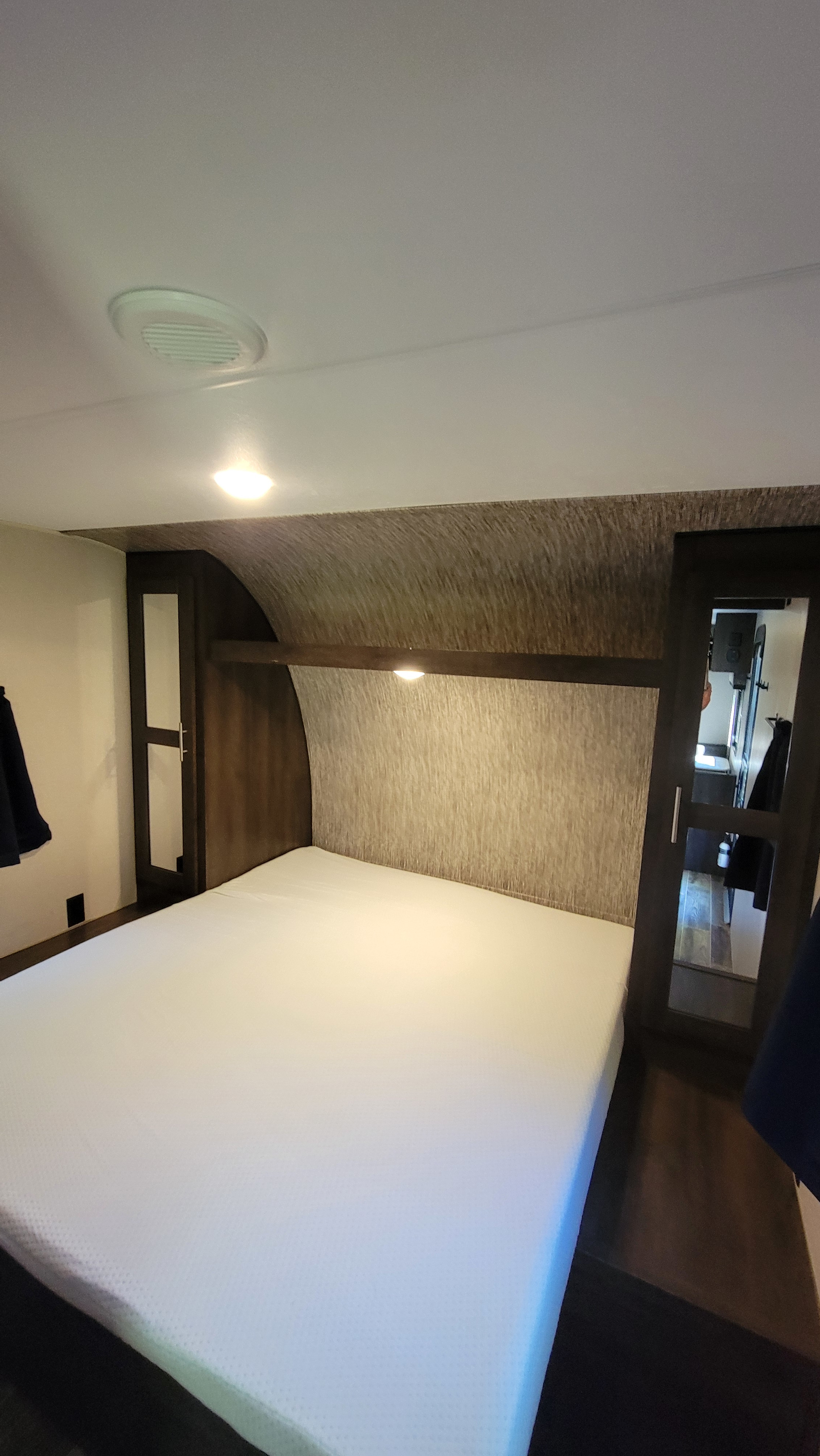 An RV rental bedroom with a white mattress, built-in storage, and overhead lighting.. KZ 260bh 2019