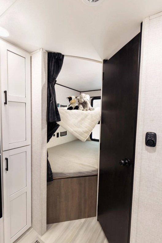 Cozy bunk beds in an RV rental, featuring plush toys on the top bunk. White storage cabinets are visible on the left.. Go Play 26BHS 2025