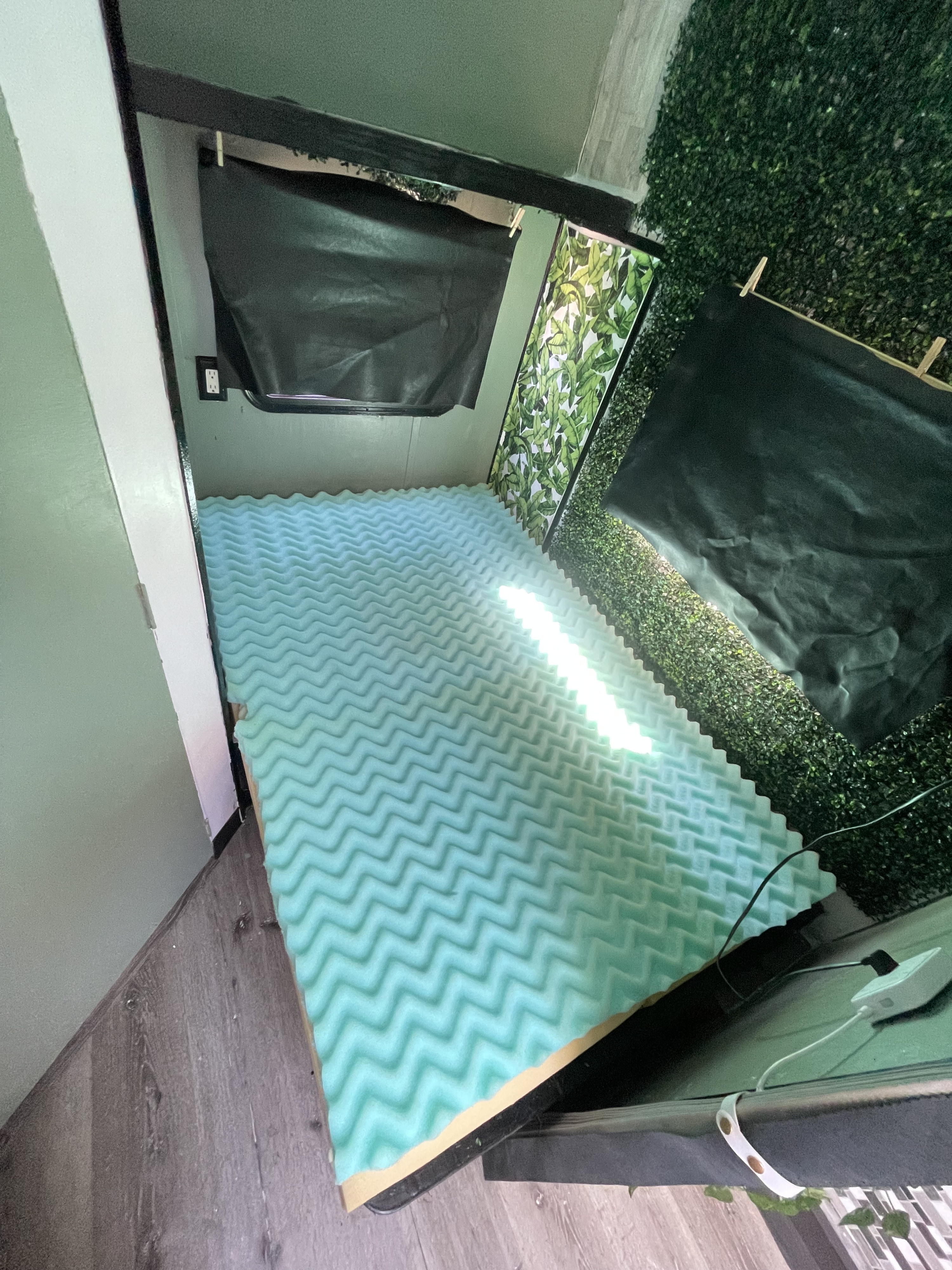 RV rental's cozy sleeping area: wavy foam mattress, artificial foliage wall, and compact setup.. Fleetwood Prowler 1996