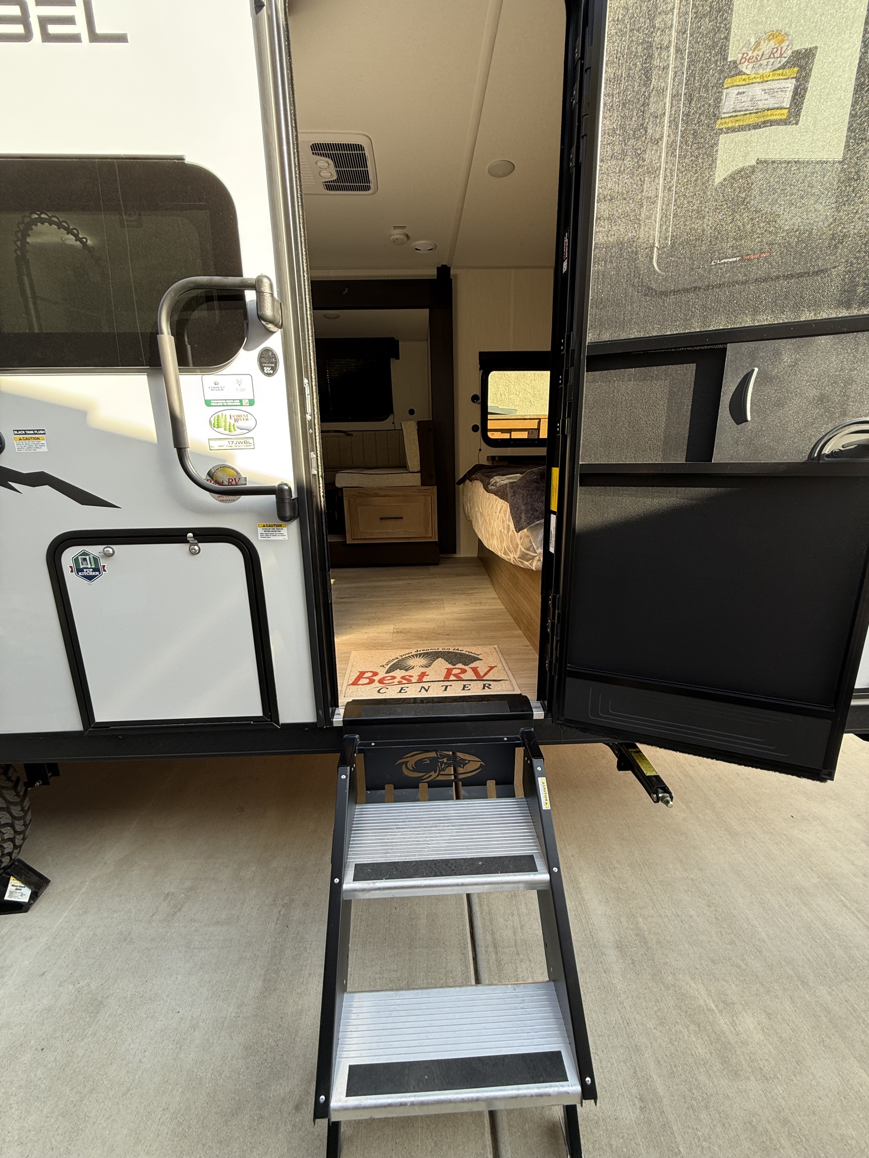 Step into this inviting travel trailer with open door and steps. See the bed, dinette, and Best RV Center mat, perfect for your next rv rental.. Cherokee WOLF PUP BLACK LABEL 17JWBL 2025