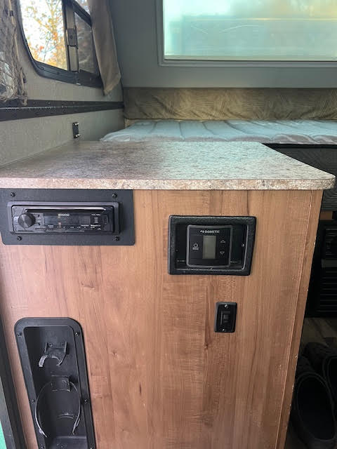 Inside an RV rental: a practical countertop, entertainment & climate controls, and a compact bed area.. Forest River Flagstaff Classic 2018