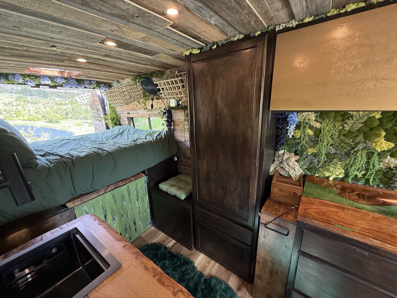 Cozy nature-themed RV rental interior with a comfy bed, kitchen, and scenic outdoor views. Perfect for your next adventure!. Dodge Ram 1500 2023
