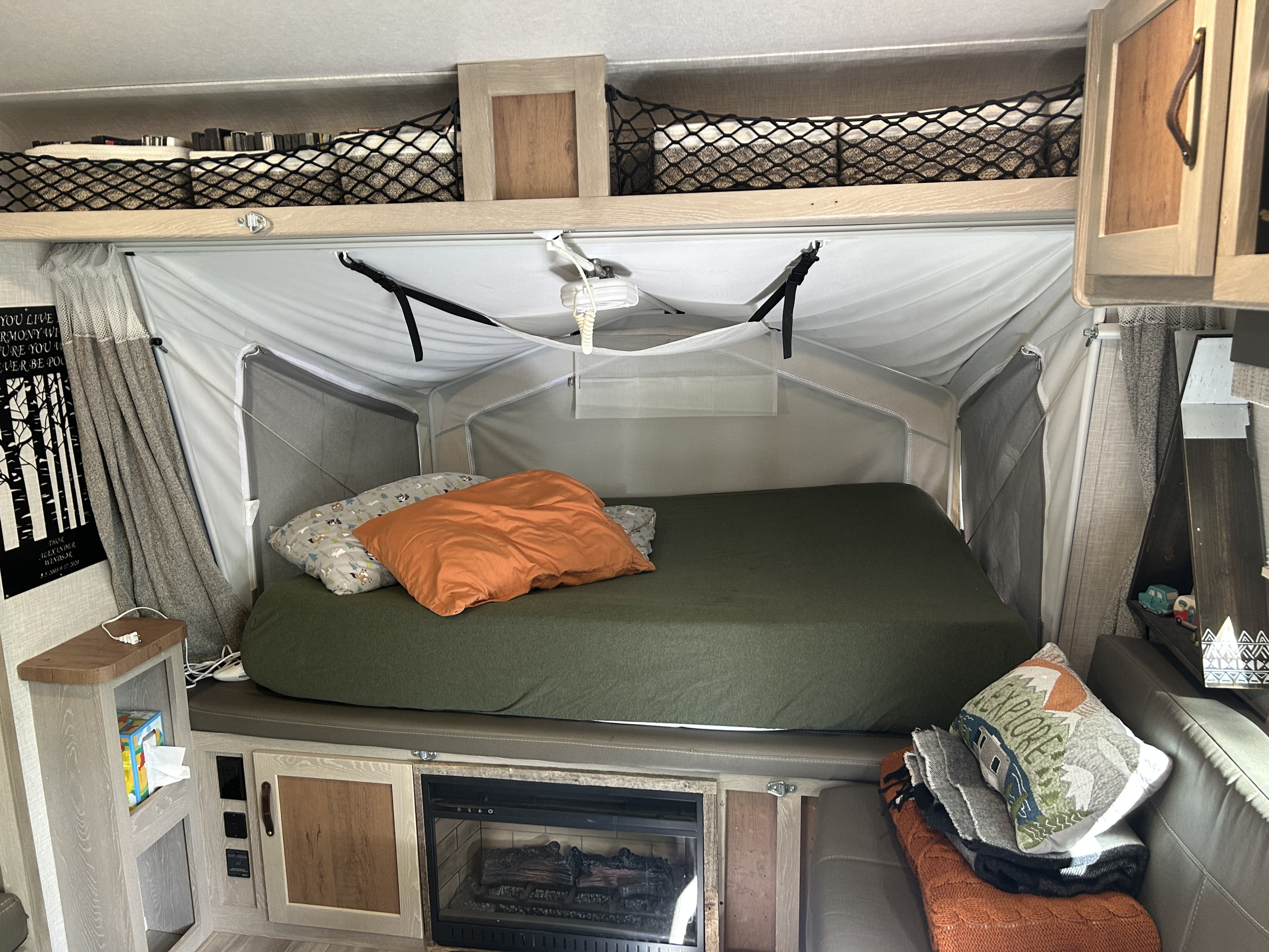 Inside an RV rental: a comfy pop-up bed, overhead storage, and a warm fireplace create a cozy home on wheels.. Forest River Flagstaff Shamrock 2022