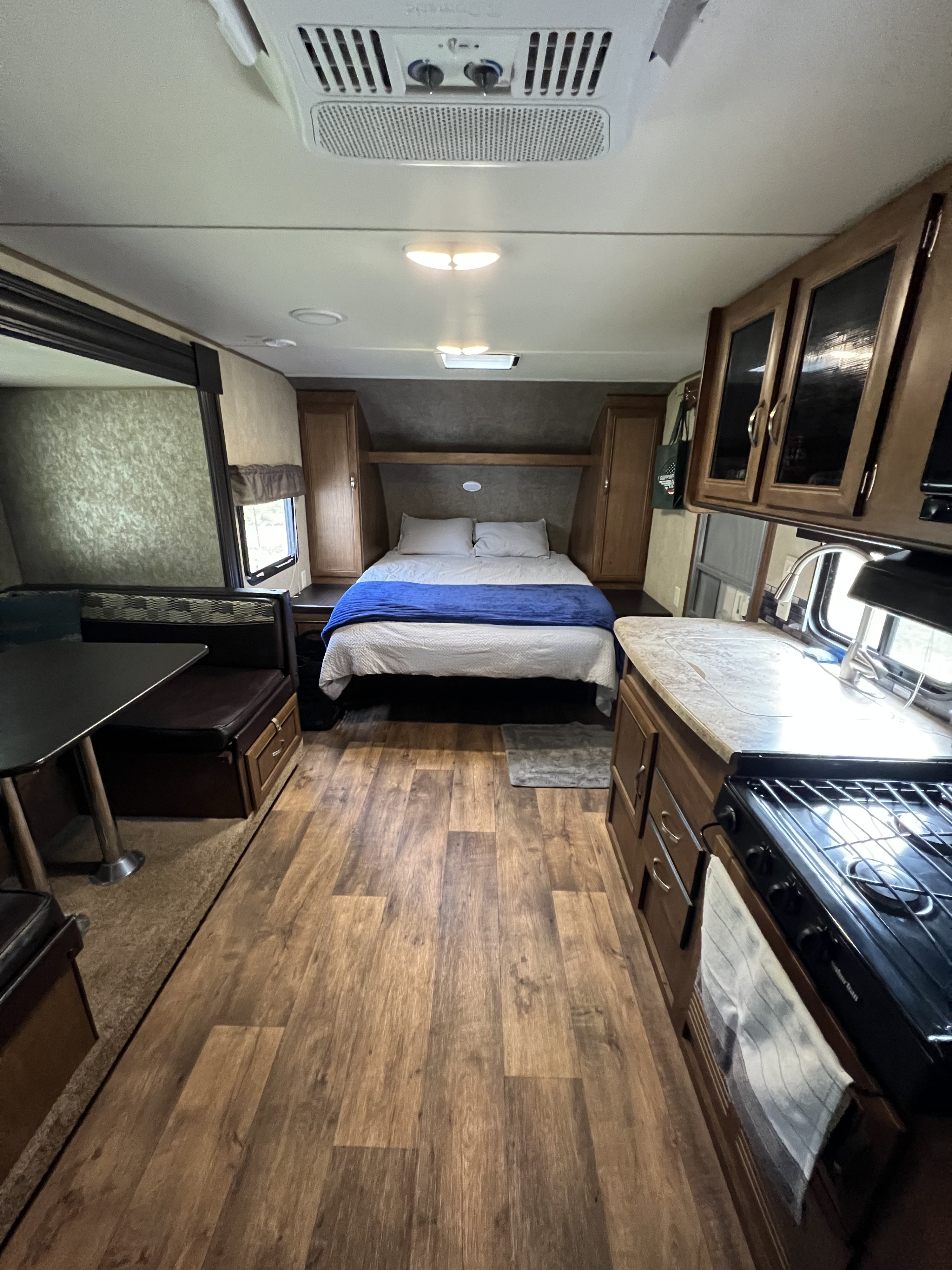 Spacious RV rental interior showcasing a bright living area with bedroom, full kitchen, and dining booth on wood floors.. Forest River Wildwood X-Lite 2017