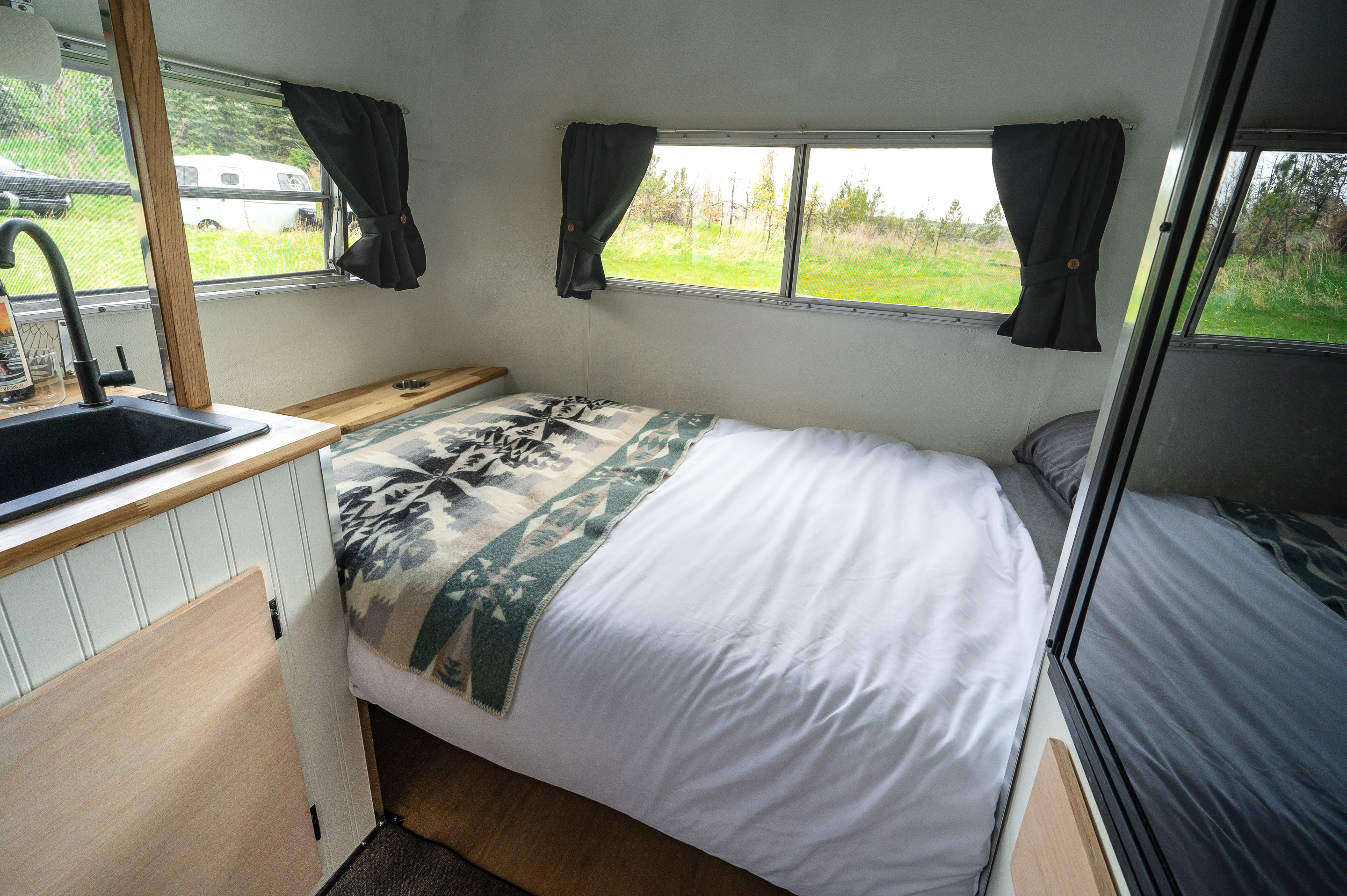 Cozy RV rental interior with bed, sink, and outdoor views for comfortable travel.. boler boler 1700 1977