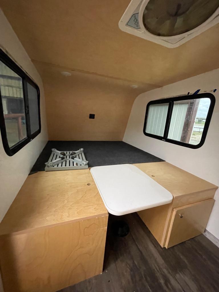**RV rental** interior: Compact camper with bed platform, stove, table, and storage for your next adventure.. RUSTIC TRAIL KODIAK STEALTH 2020