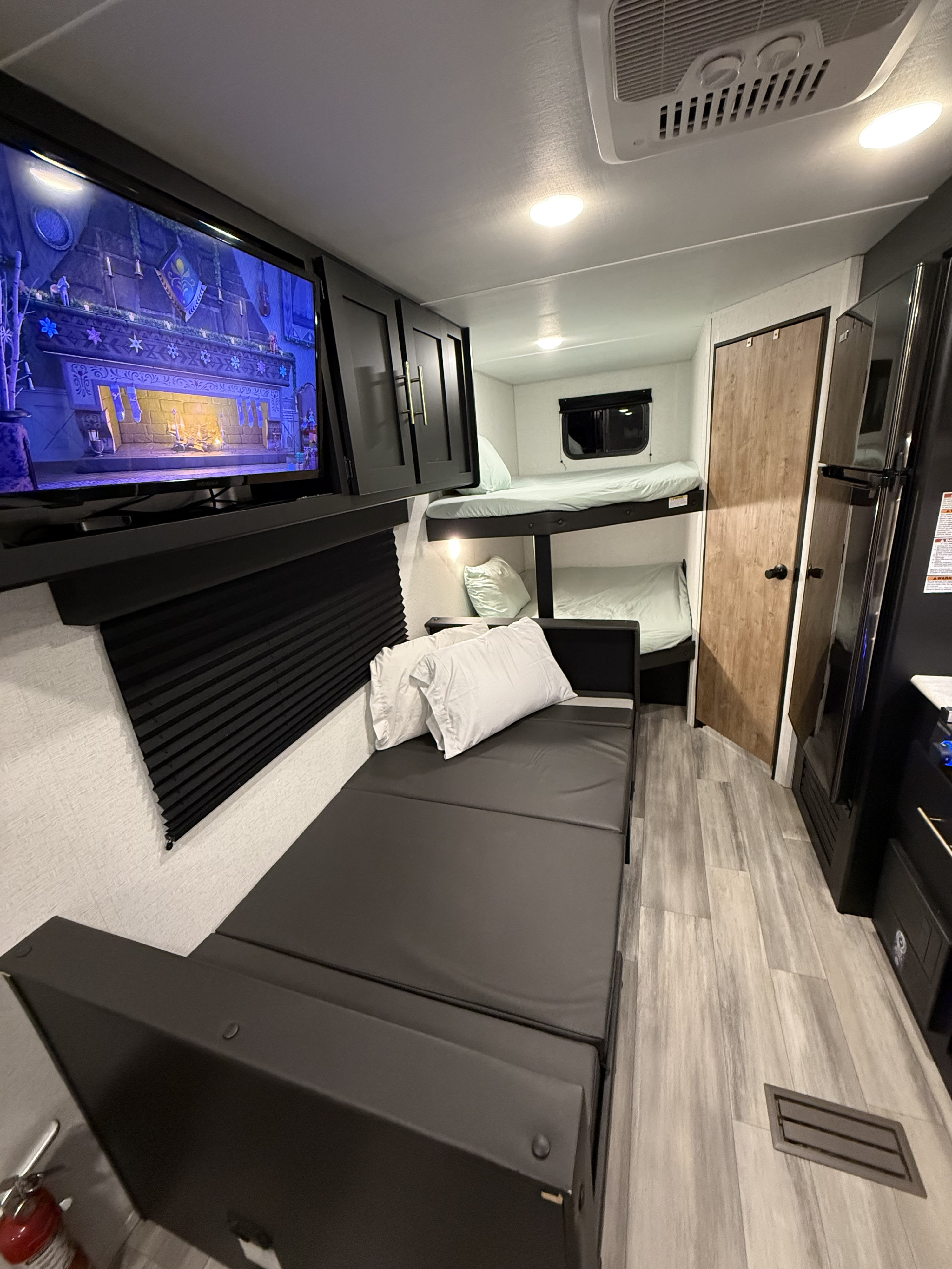 Inside a comfortable RV rental: living space with entertainment on TV, fold-out sofa, and cozy bunk beds.. Keystone RV Springdale 2023