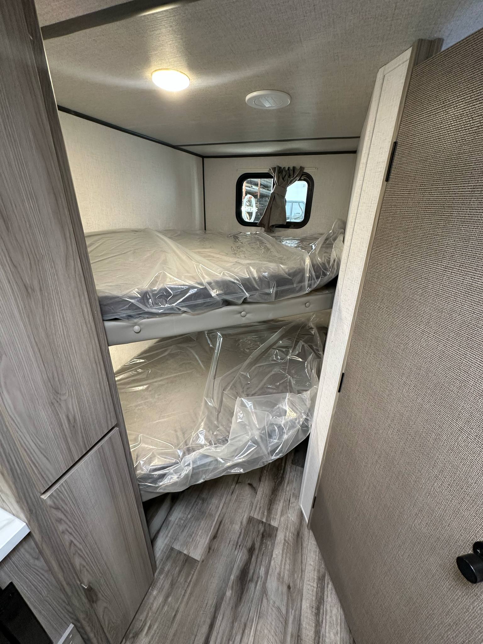 Cozy bunk beds, still wrapped, in a clean RV rental interior with wood-look floors. Ready for your next adventure.. Forest River Salem FSX 266BHLE 2025