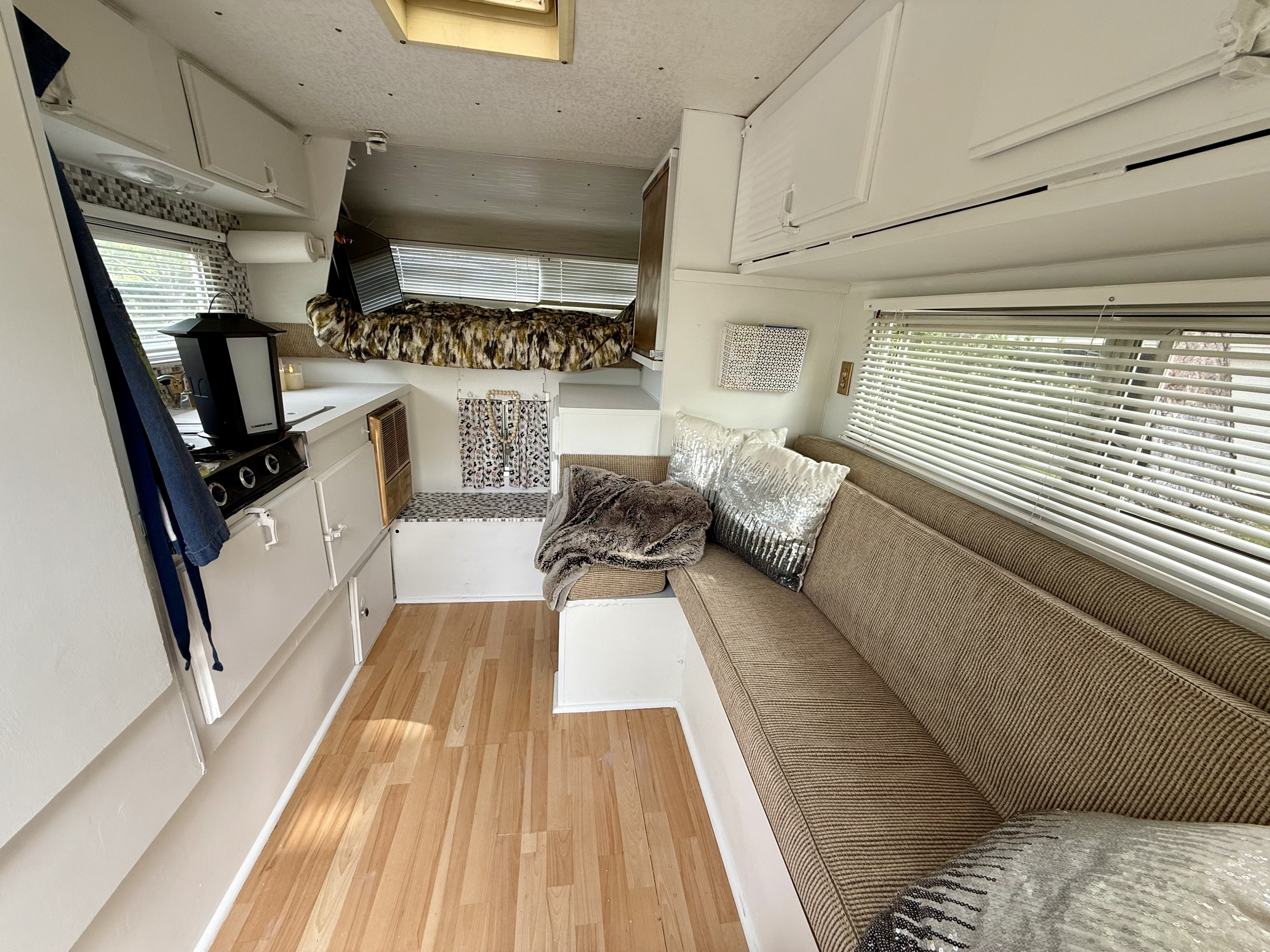 Explore this RV rental's cozy interior: a kitchenette, a patterned bunk bed, and a long couch with sparkly pillows.. Ford Ford F150 1989