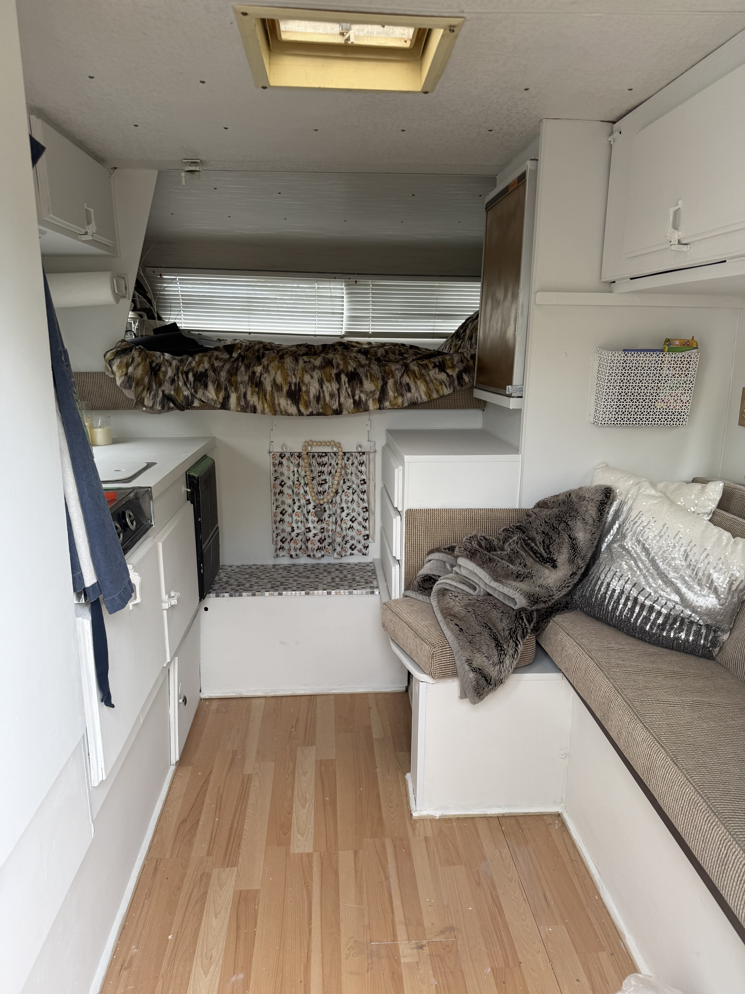 Step inside this cozy RV rental, featuring a compact interior with a cab-over bed, kitchen counter, and built-in dinette.. Ford Ford F150 1989