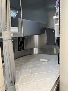 RV rental bedroom: This Airstream RV interior features a clean, quilted mattress, shiny walls, and storage for your trip.. Airstream Flying Cloud 2023