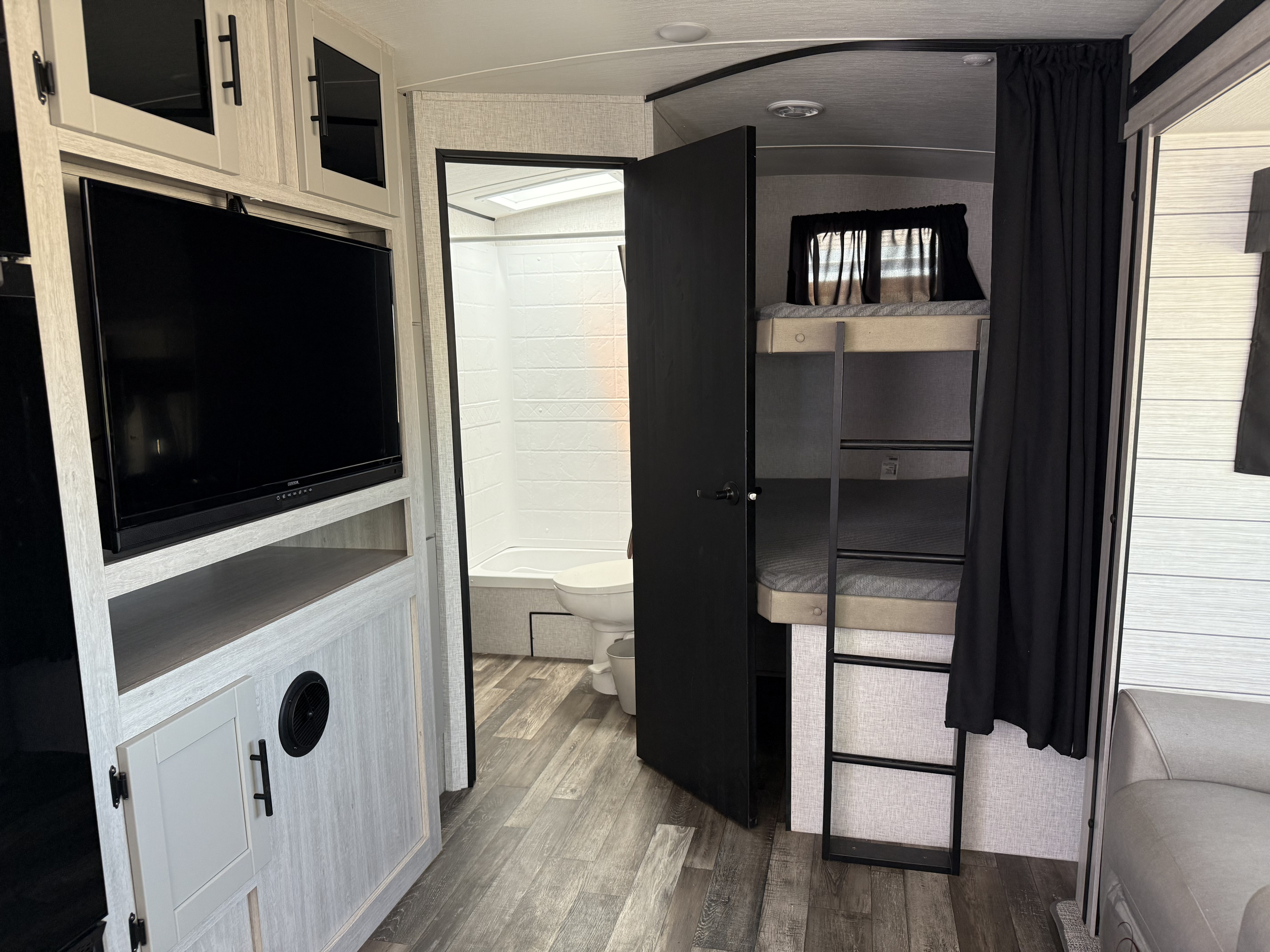 RV rental interior featuring a cozy living area with TV, bunk beds, and a functional full bathroom.. Crossroads RV 272BH 2024