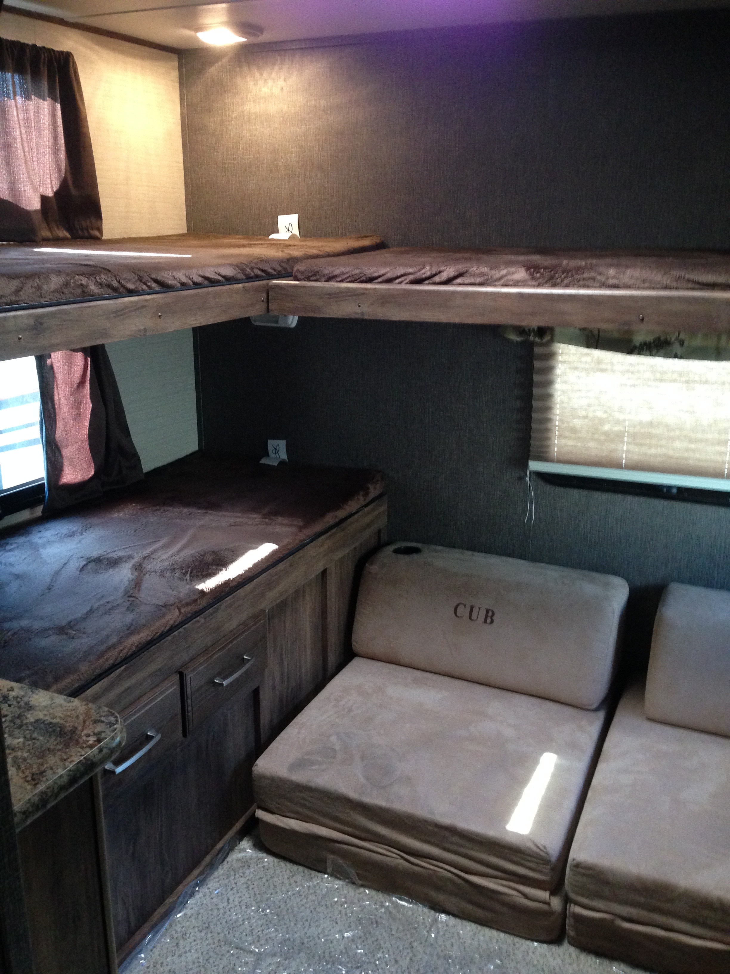 RV rental interior showing bunk beds, window, and "CUB" seating area. Ideal compact sleeping and living space for travel.. Keystone RV Cougar 2016