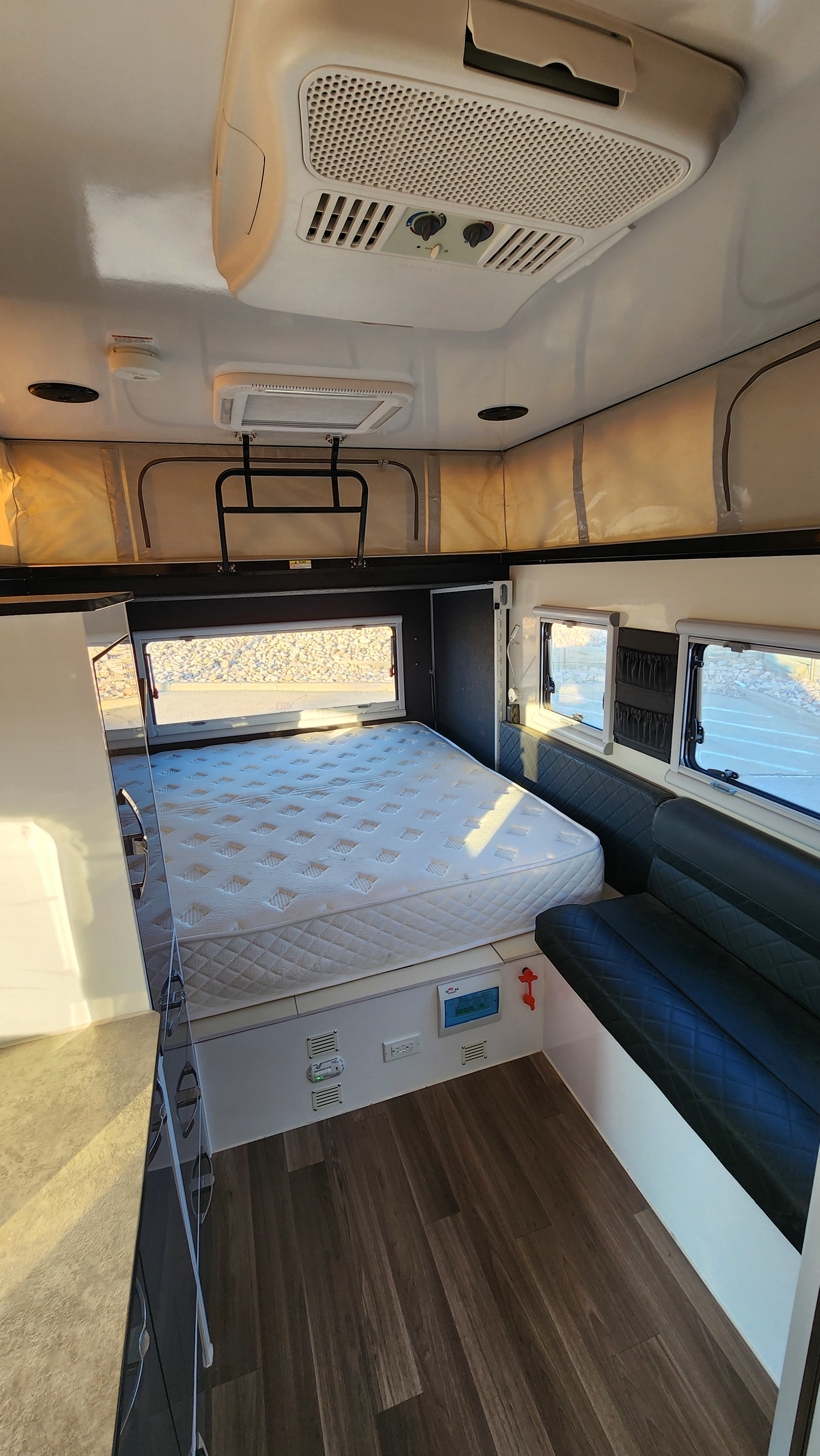 Explore this RV rental's spacious interior: a queen bed, seating, and a pop-top canvas wall indicate a versatile camper layout.. AUSRV X13 2022
