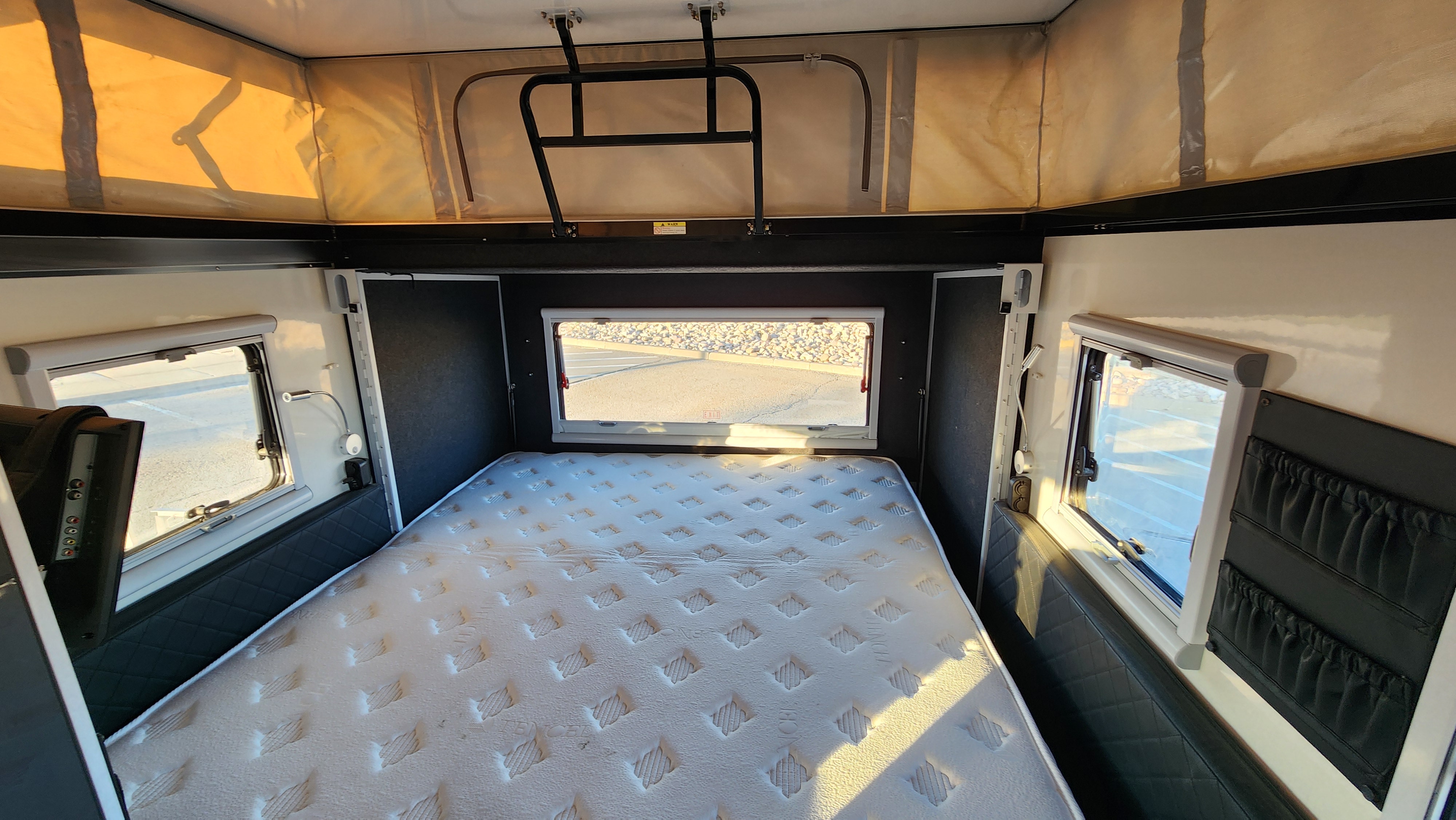 Spacious RV rental interior with a large bed, windows, and pop-up roof. Ideal for comfortable travel.. AUSRV X13 2022