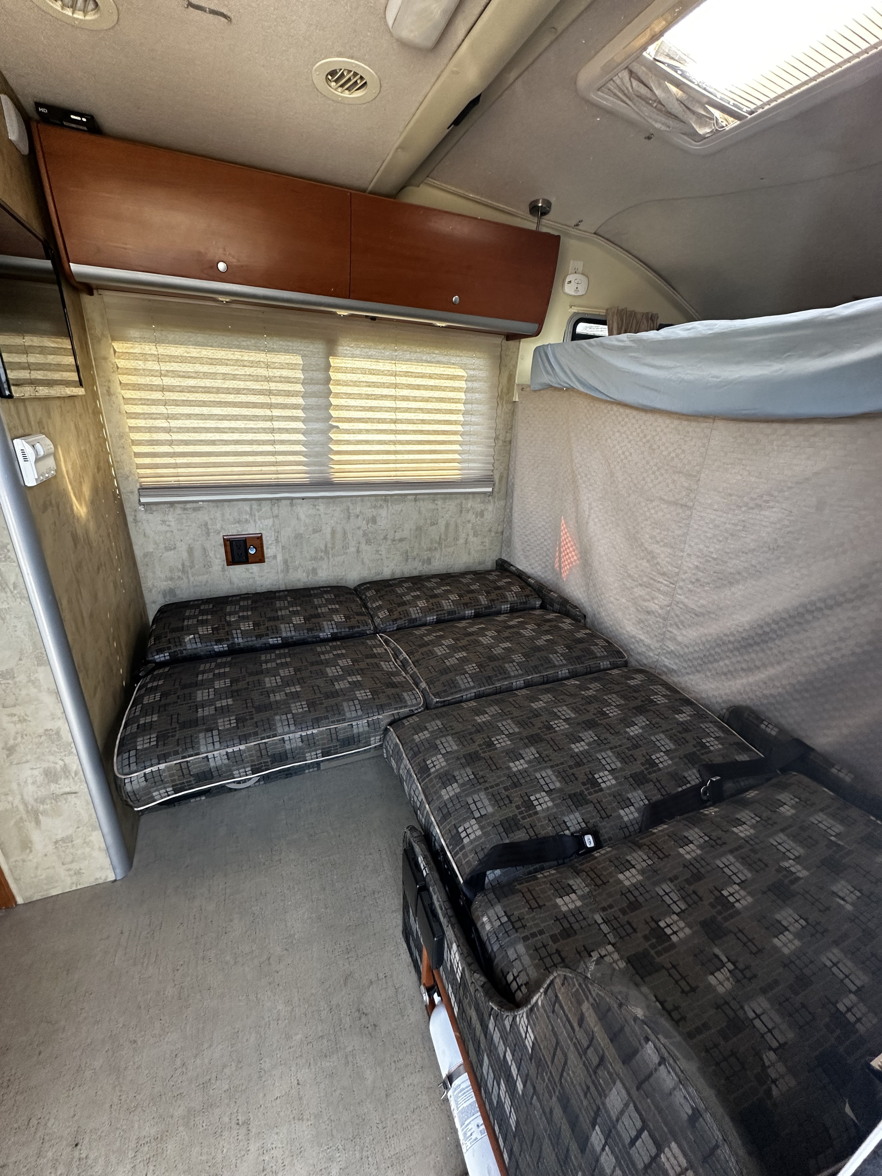 RV rental interior features a convertible dinette/bed, overhead cabinets, and window blinds, ready for your next adventure.. Winnebago View 2006