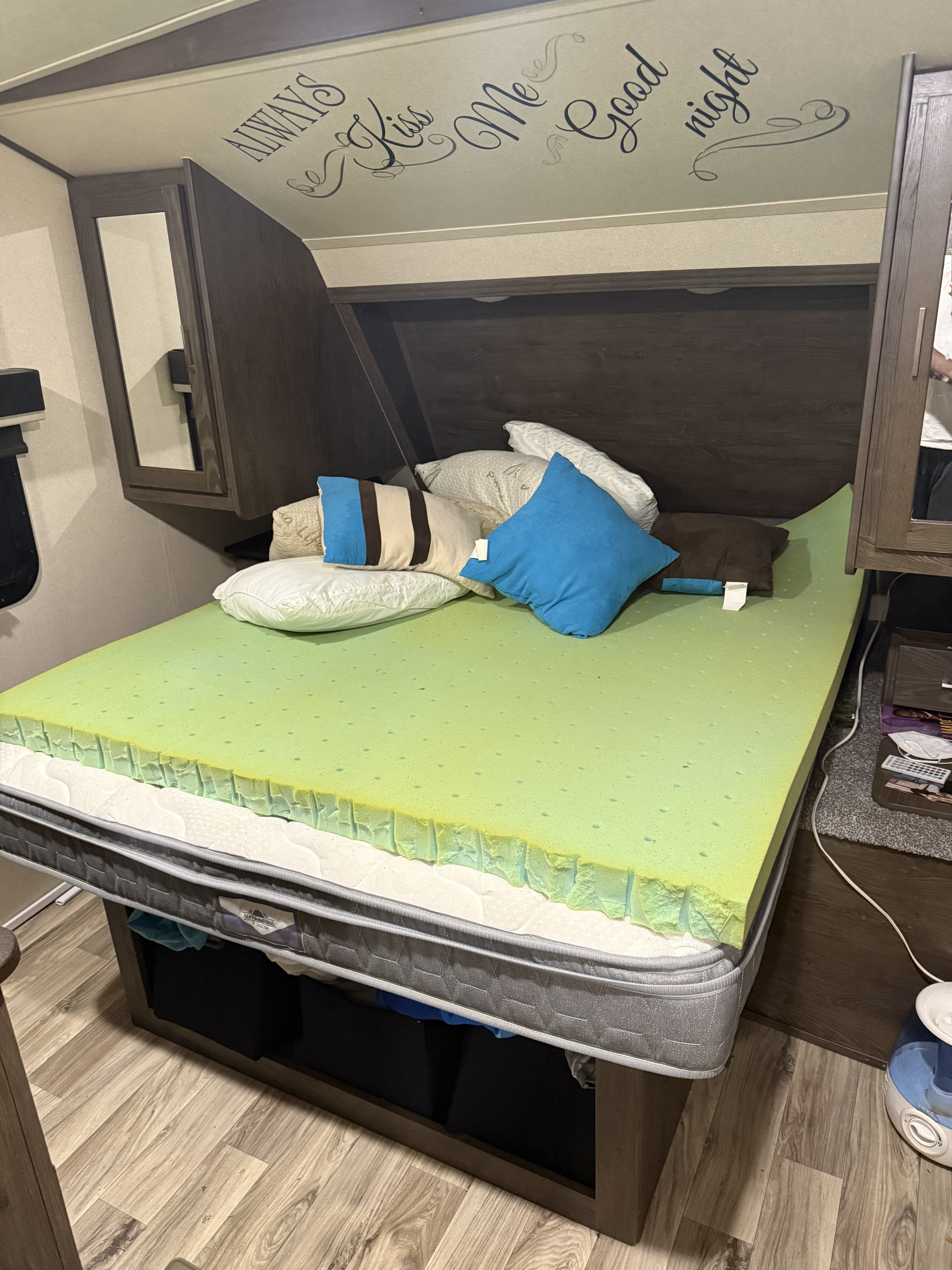 RV rental bedroom with a comfortable bed, vibrant green memory foam topper, and "Kiss Me Good night" headboard decor.. Forest River Salem Hemisphere Lite 2018