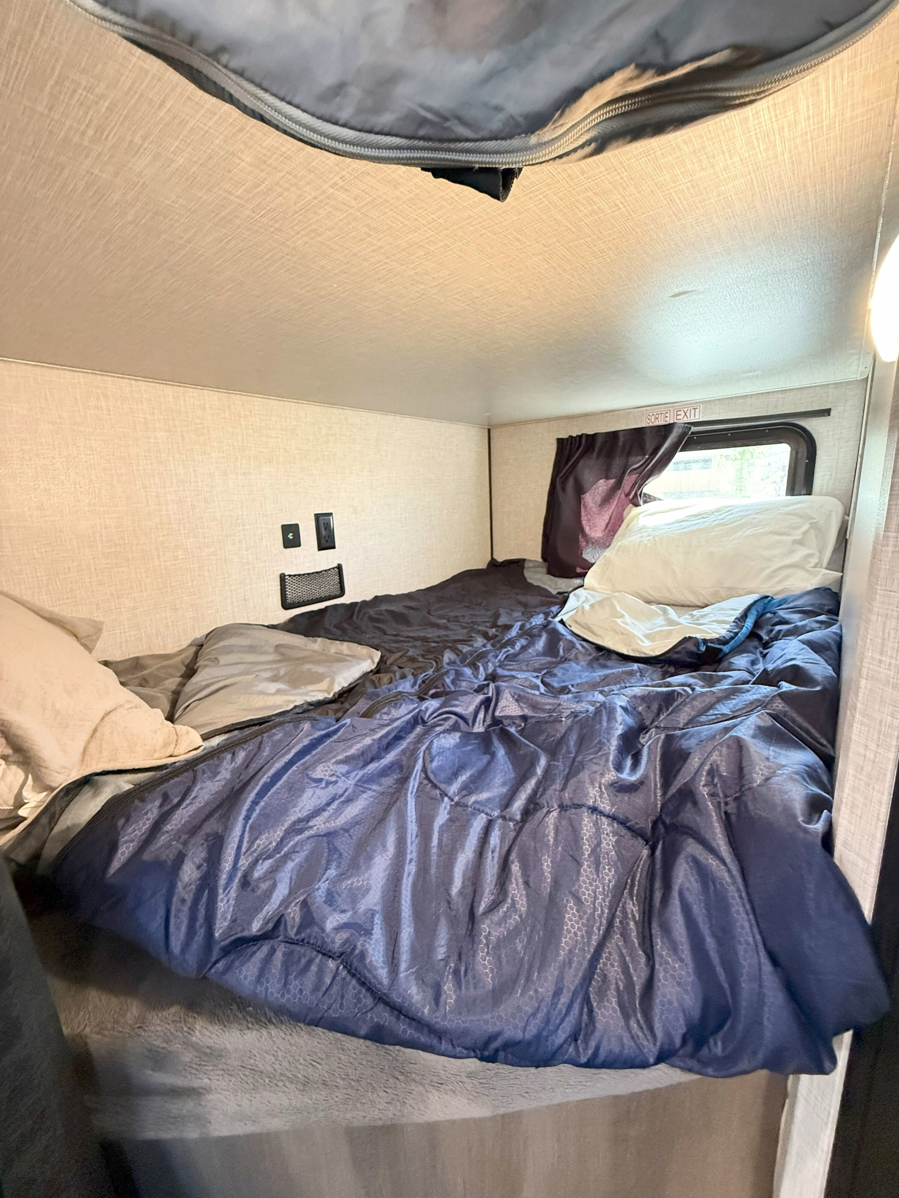 Cozy RV rental interior with a bunk bed, showing the sleeping area, window, and emergency exit.. Starcraft Autumn Ridge 2023