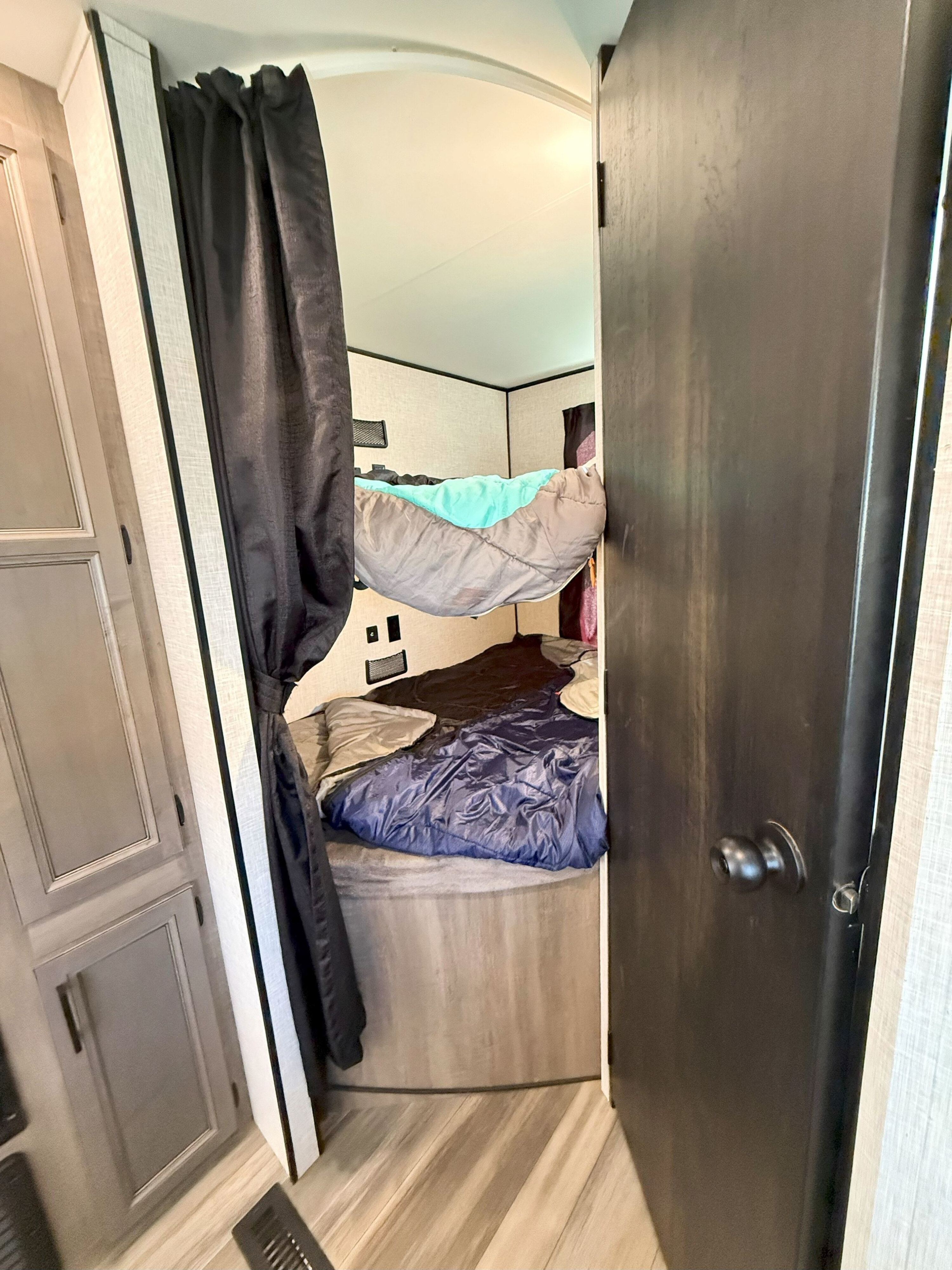 RV rental interior: Cozy bunk beds with sleeping bags and a dark privacy curtain create a sleeping area.. Starcraft Autumn Ridge 2023