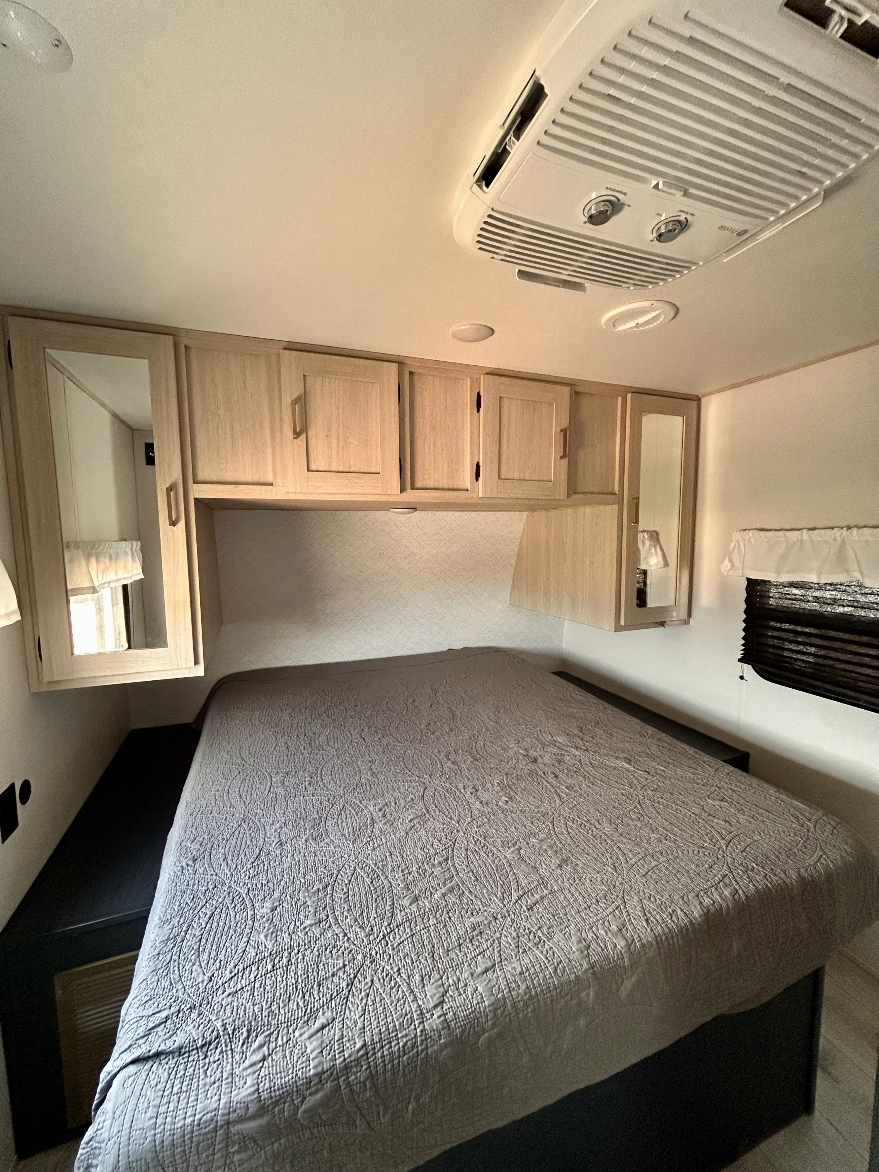 Comfortable RV rental bedroom with a large bed, overhead cabinets, and AC unit, ideal for your next adventure.. Primetime Avenger 2025