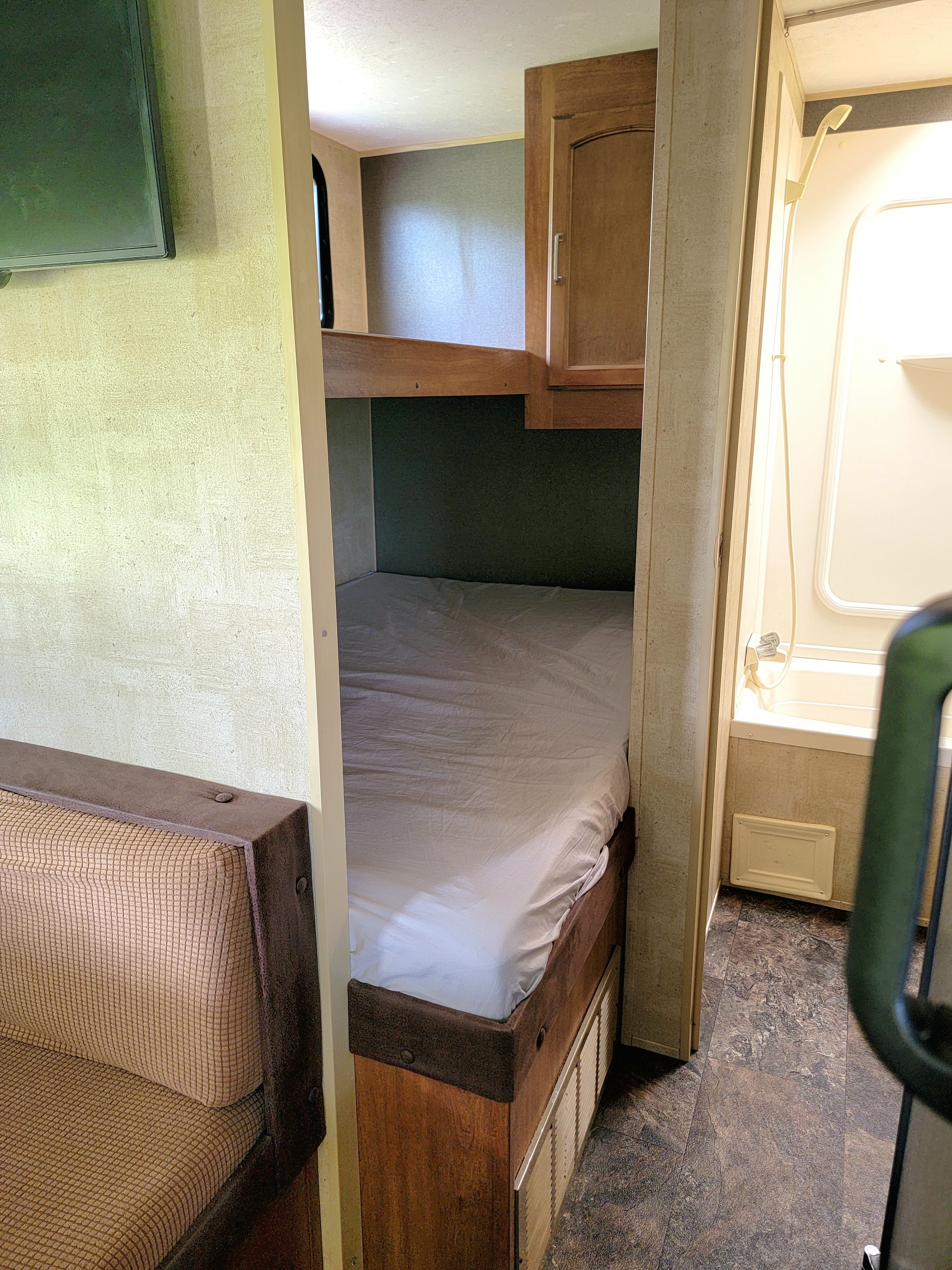 Cozy rv rental interior featuring bunk beds, a seating area, and a compact bathroom. Perfect for travel.. Keystone RV Summerland 2015